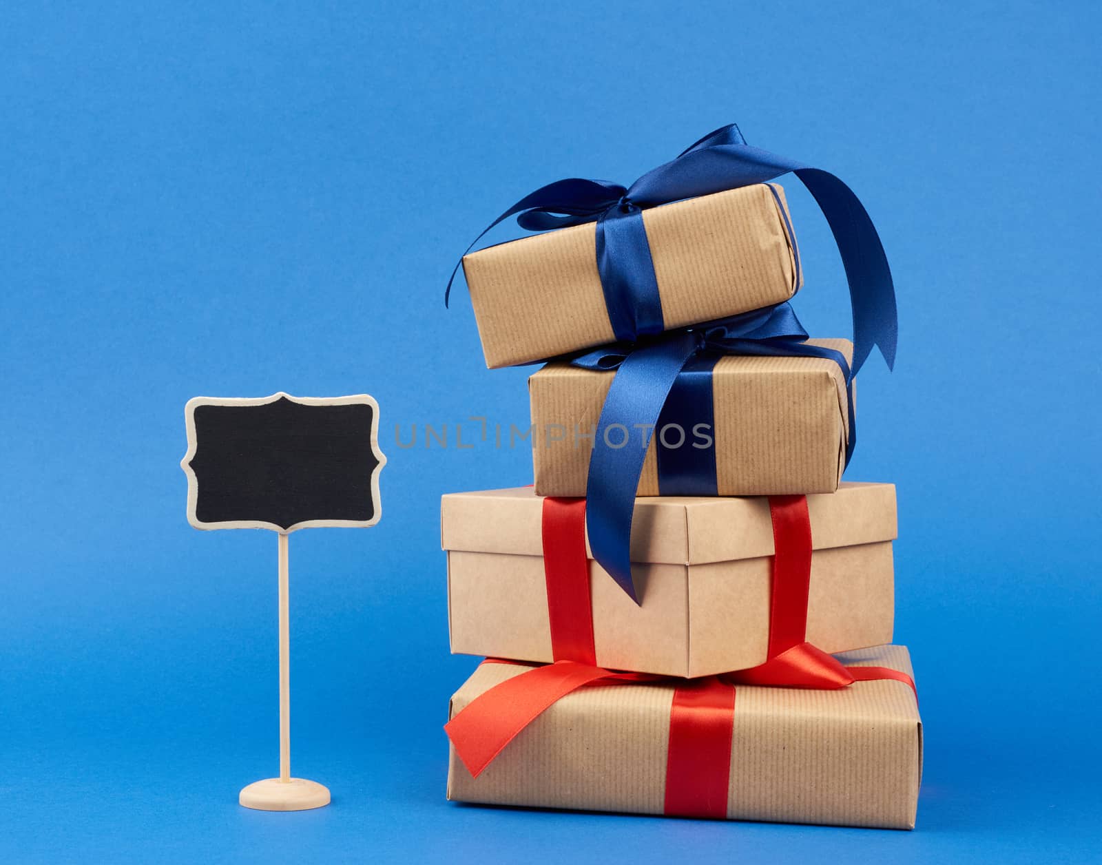 wooden pointer and rectangle box wrapped in brown kraft paper and tied with a silk ribbon, gift on a dark blue background