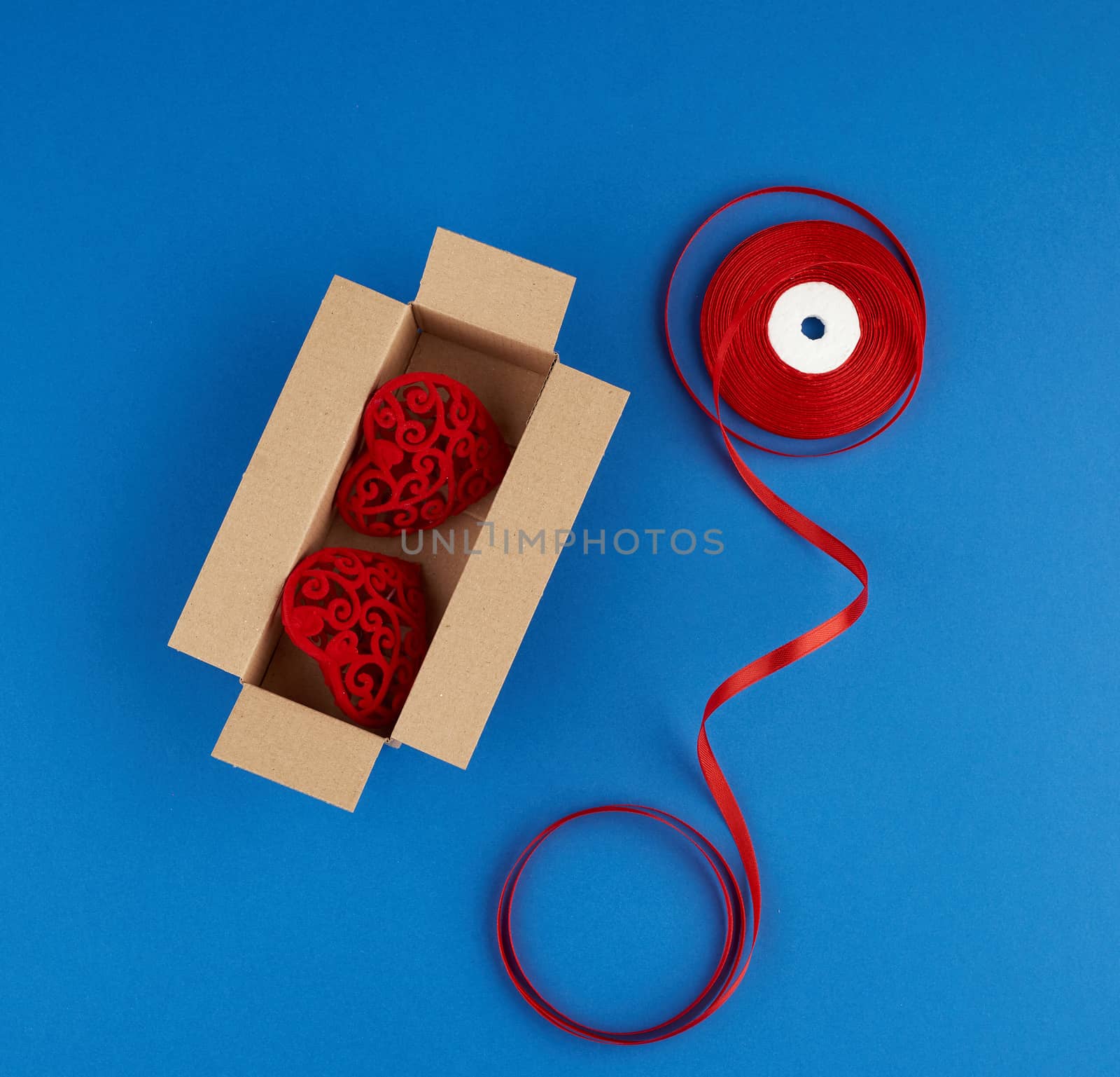 rectangular brown cardboard box and red silk ribbon on a blue background, top view