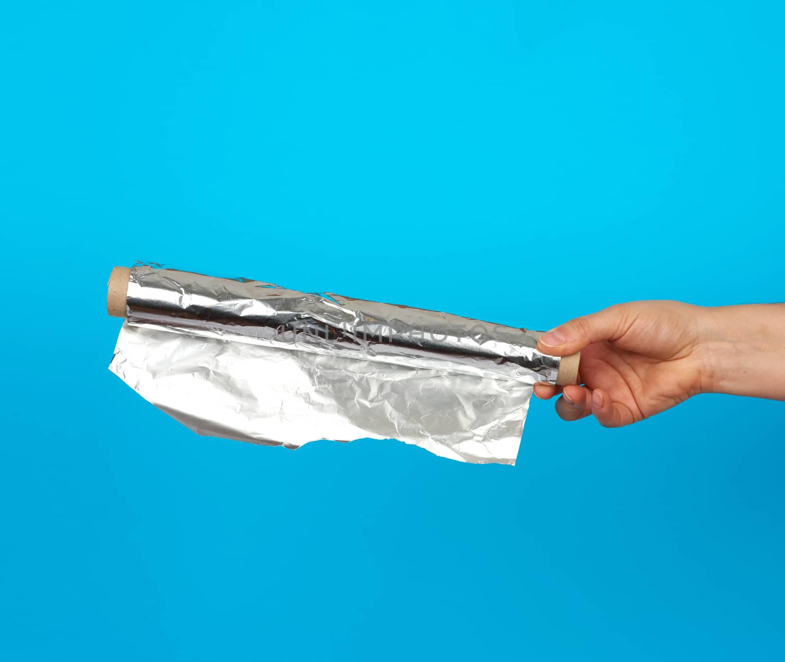 hand holds a roll with twisted gray shiny foil on a blue background, food packaging