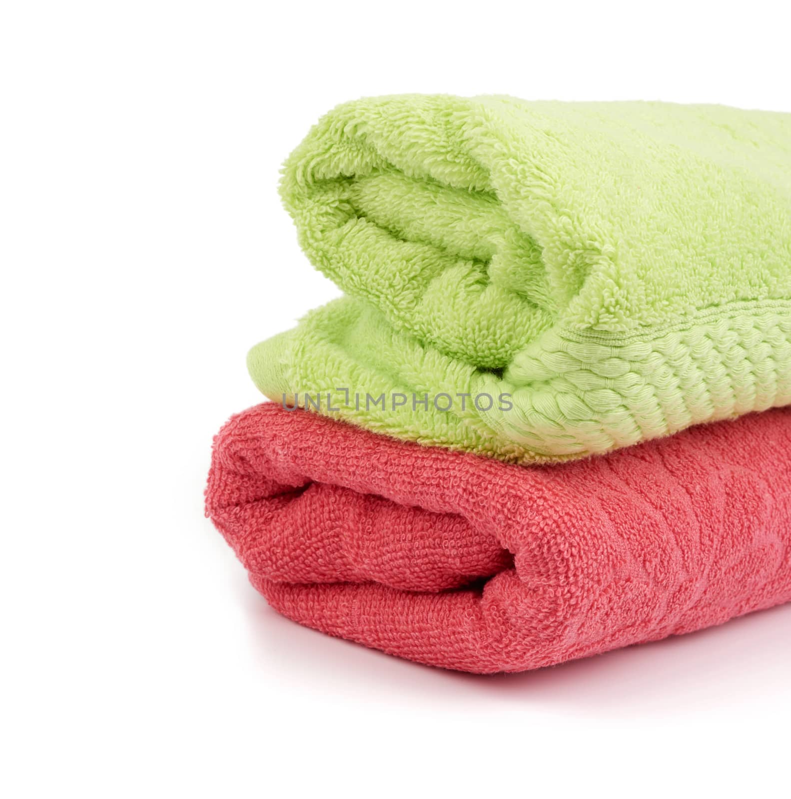 stack of colored cotton terry folded towels on a white backgroun by ndanko