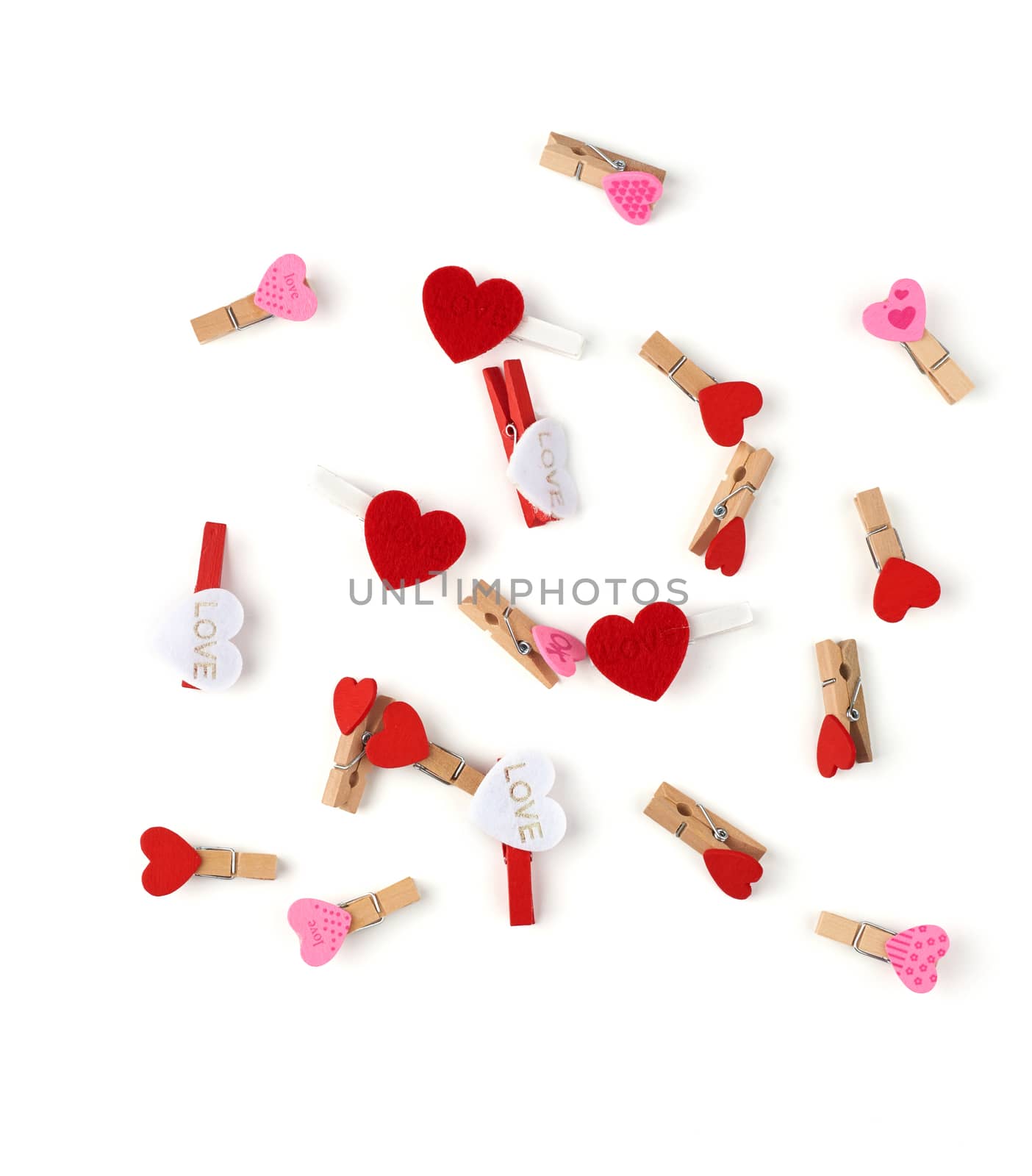 wooden decorative clothespins scattered on a white background with red hearts, top view