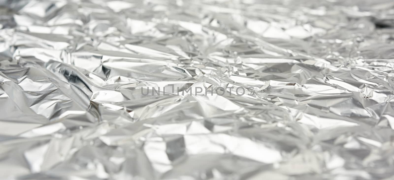 texture of frosted crumpled piece of foil, packaging material for food and objects, full frame. selective focus
