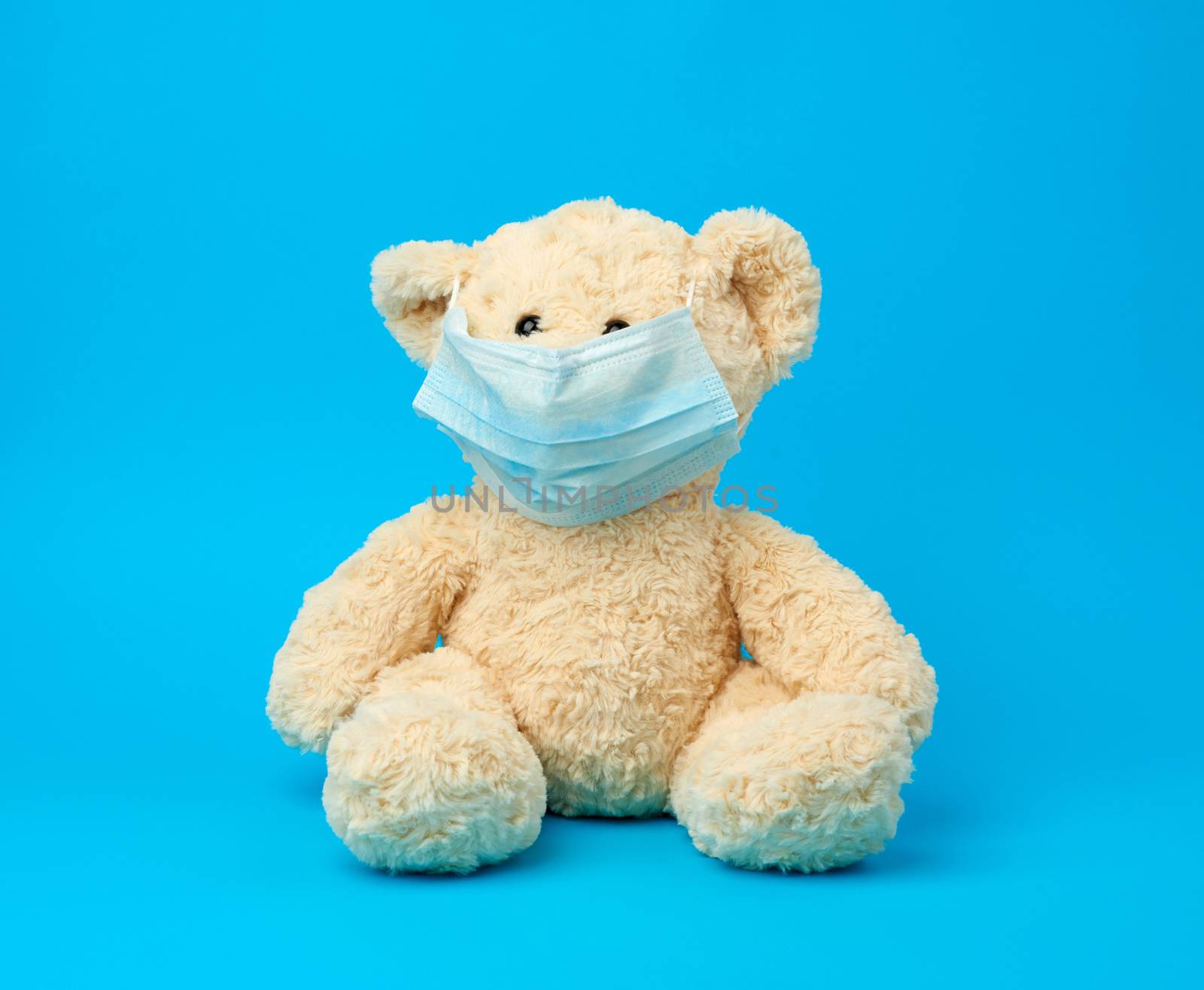 big teddy bear are sitting in medical masks on a blue background, concept of protection from respiratory disease, virus and individual respiratory protection