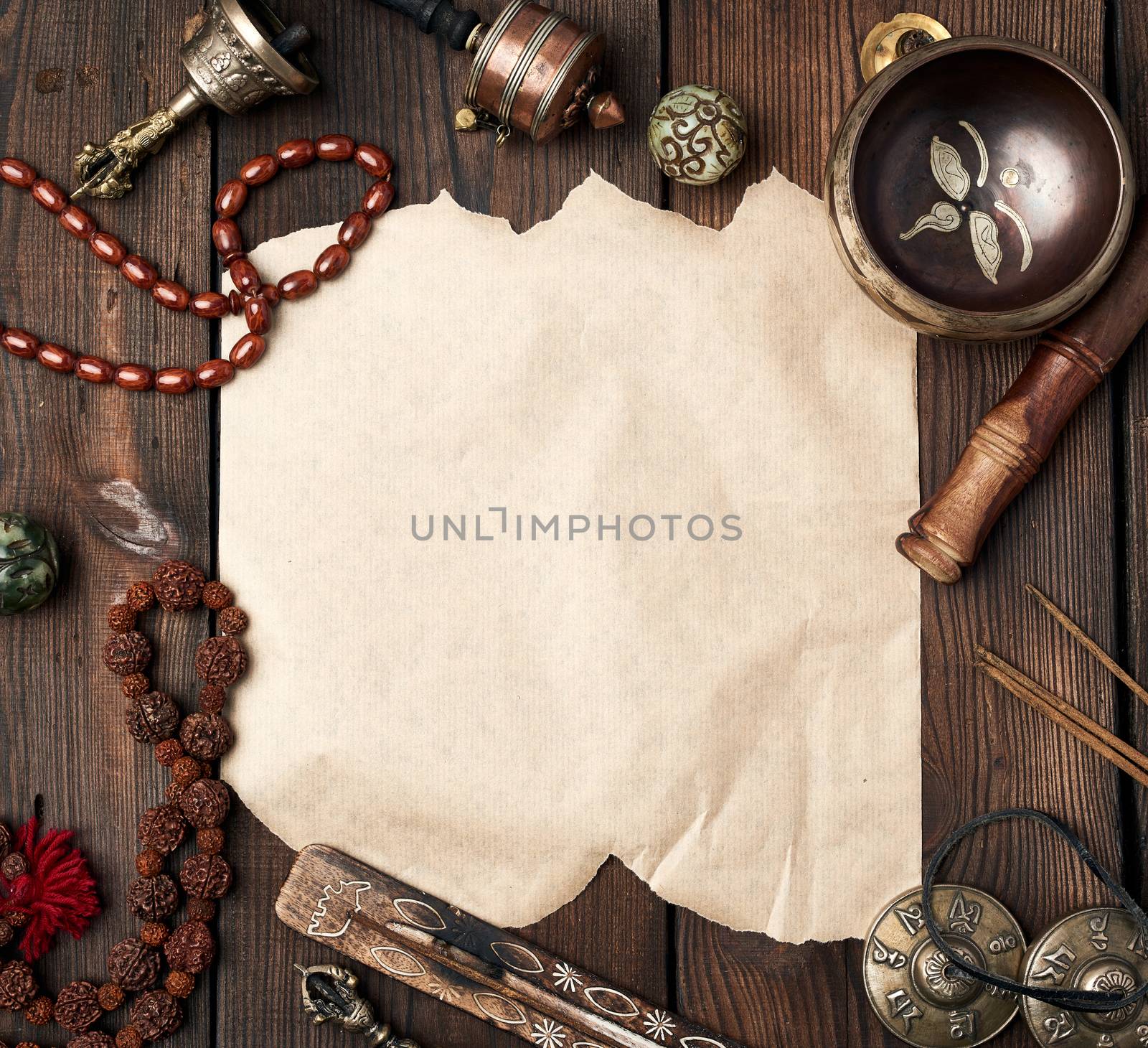 tibetan religious objects for meditation and alternative medicine, empty crumpled brown sheet of paper on a brown wooden background, top view