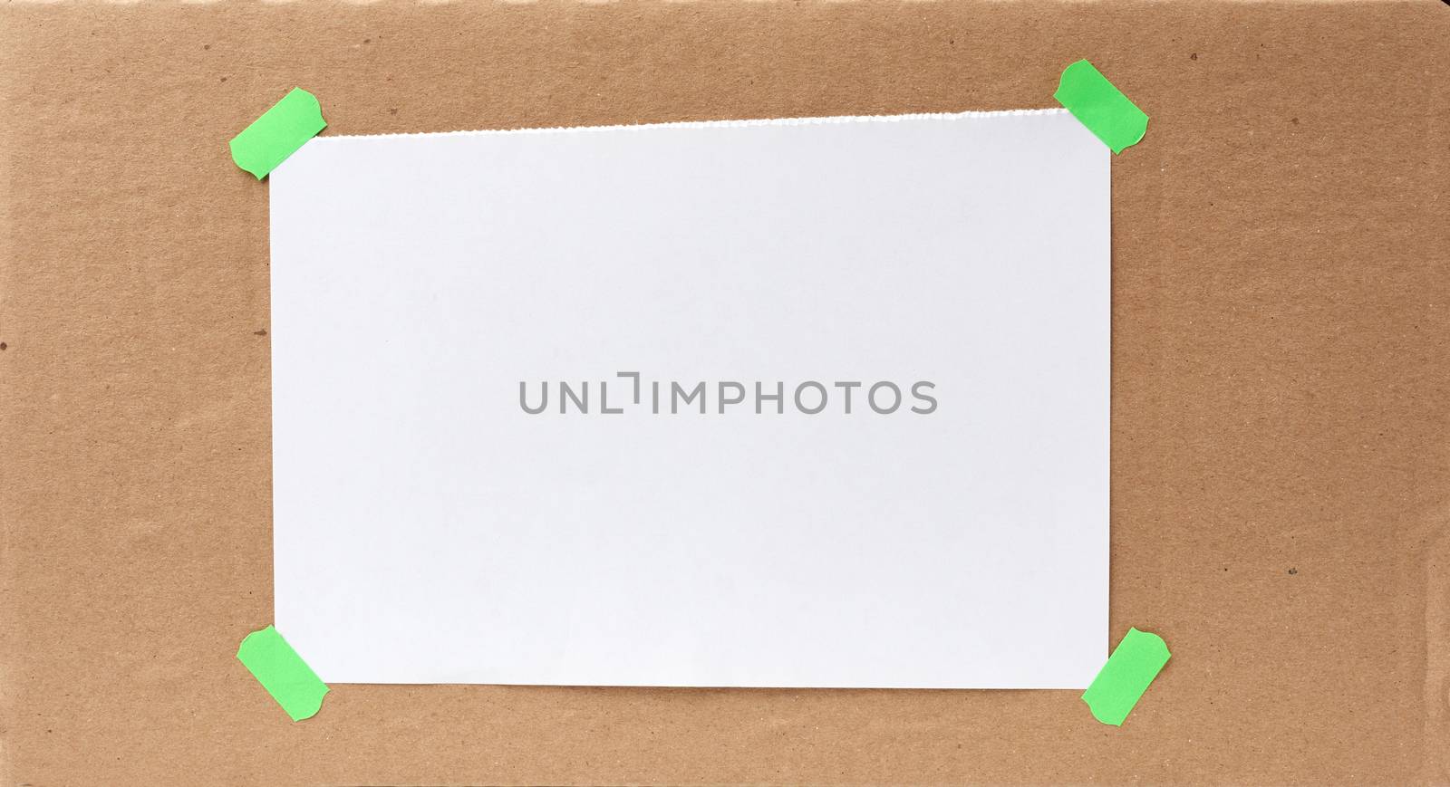 blank paper ad with torn edges attached with a green velcro on a brown cardboard surface, backdrop for sales and messages, copy space