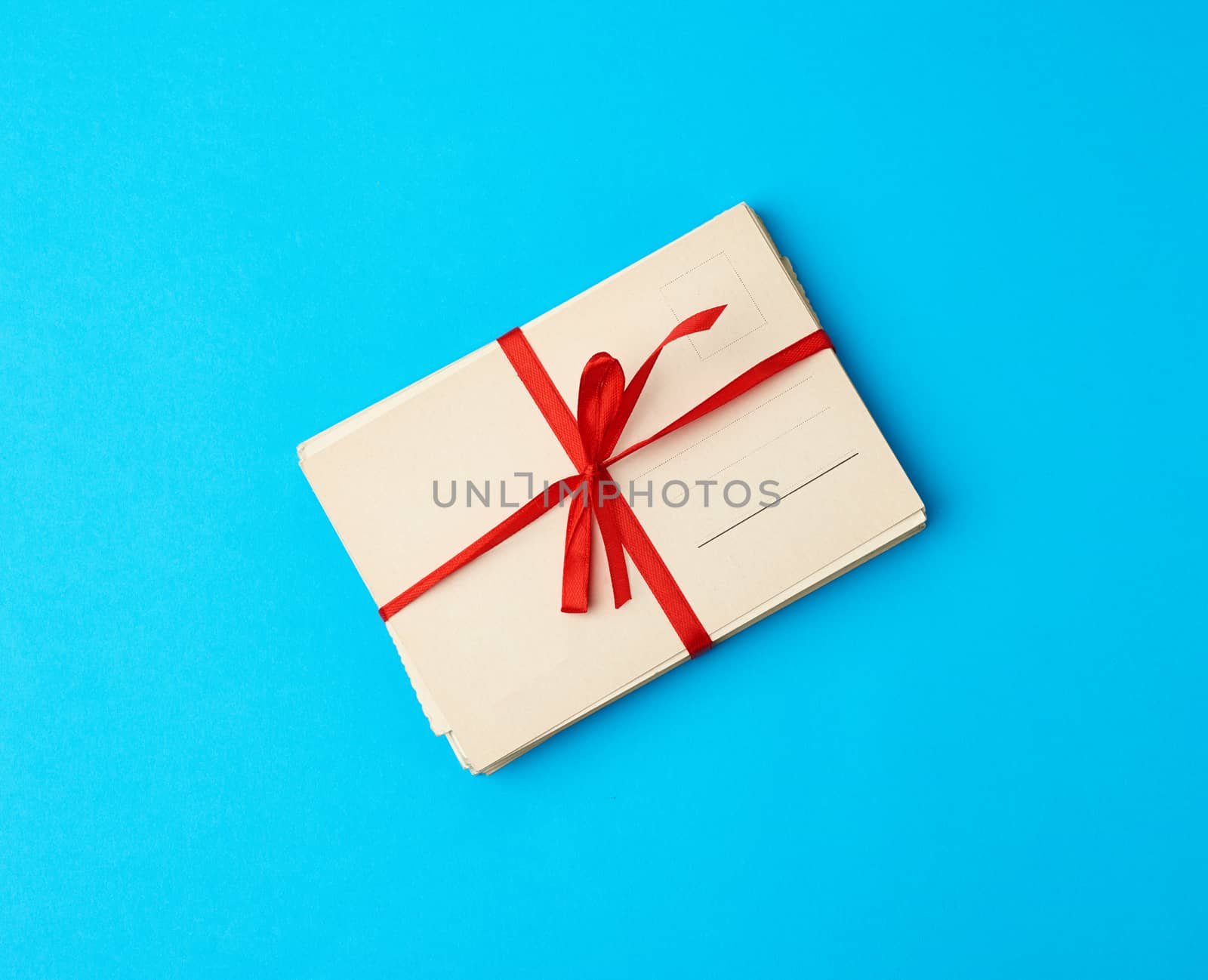 tied red silk ribbon rectangular vintage greeting card, blue background, top view