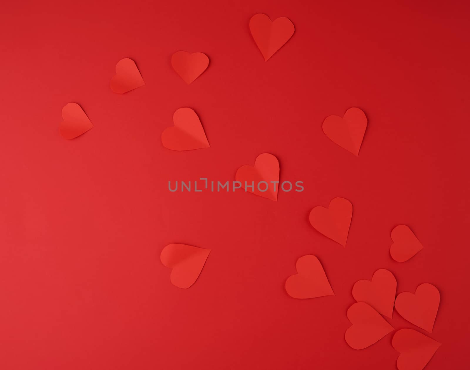 hearts cut out of red paper on a red background, festive backdrop for Valentine's Day, flat lay