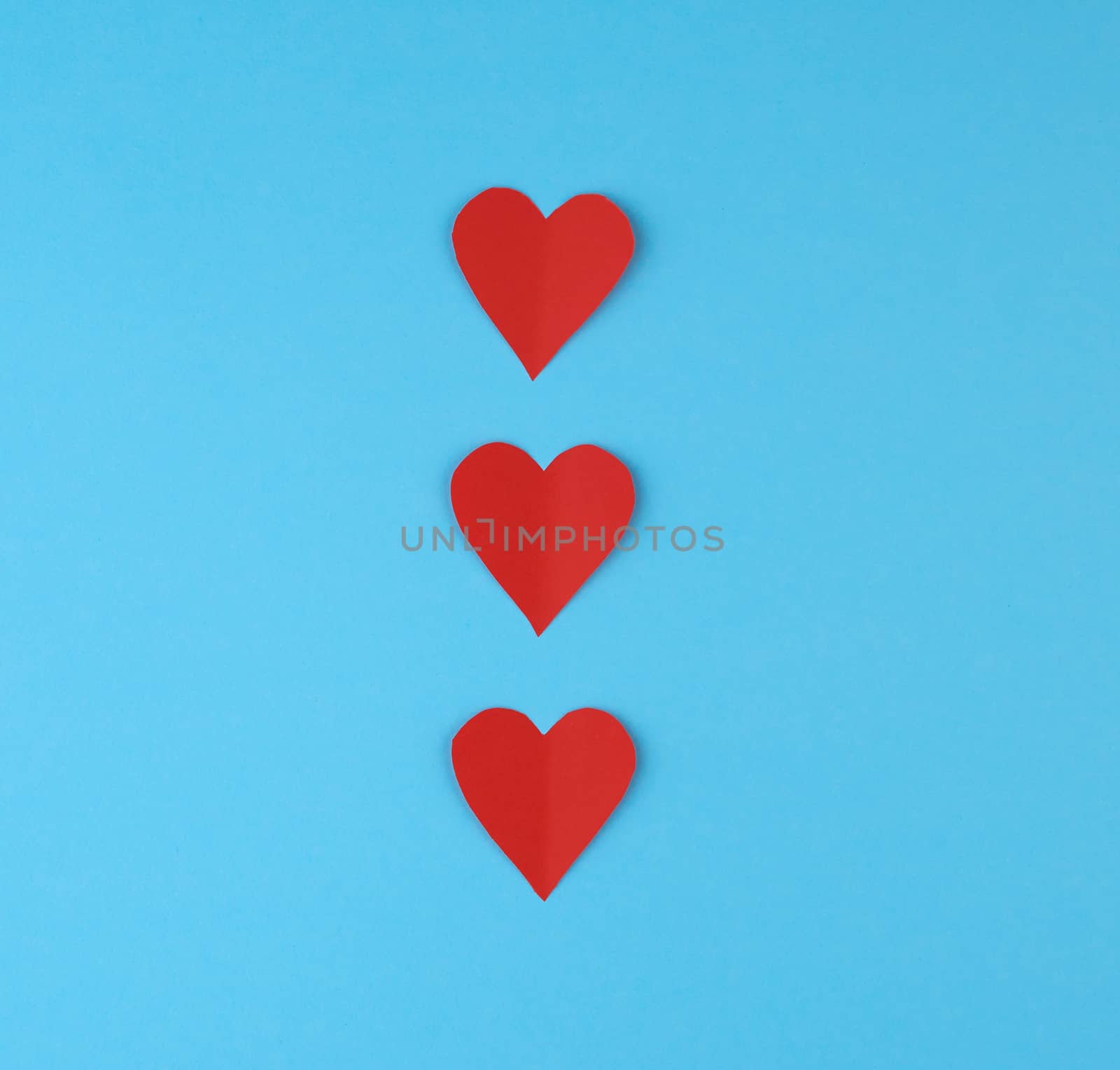 hearts cut out of red paper on a blue background, festive backdrop for Valentine's Day, copy space