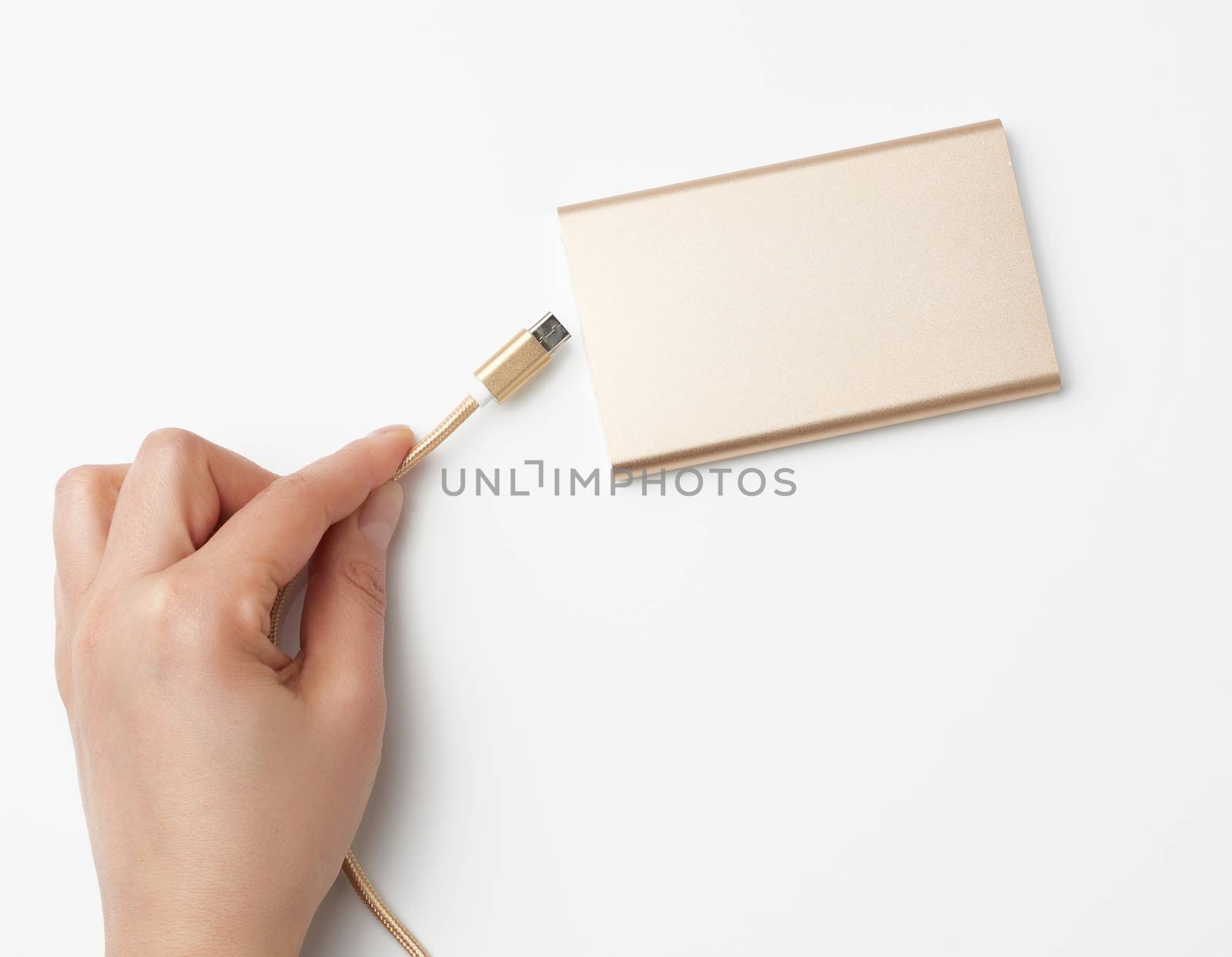 hand holding a portable power bank and a golden cable on a white background, top view