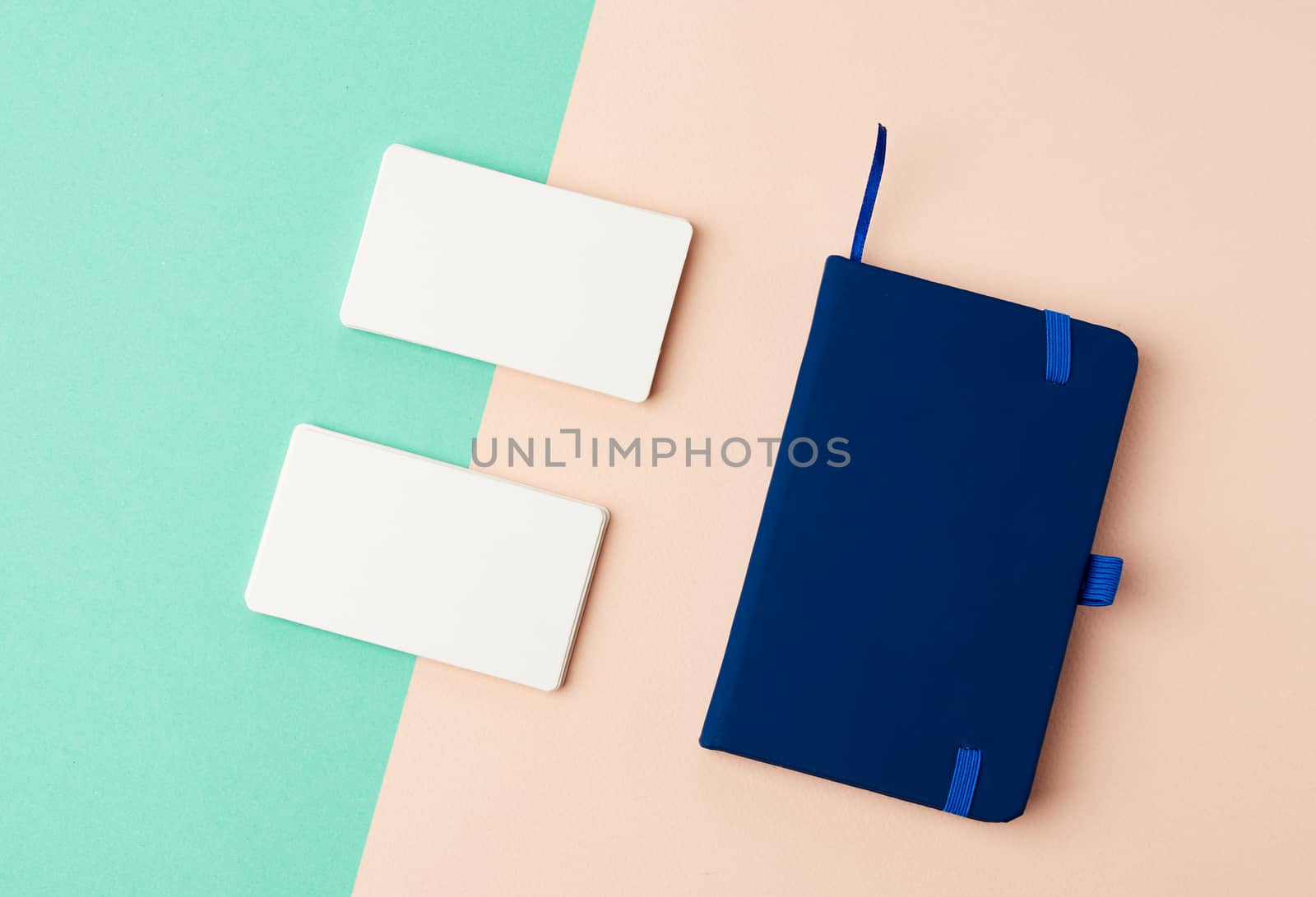 stack of rectangular white blank business cards and blue notebook on a green beige background, backdrop for the designer