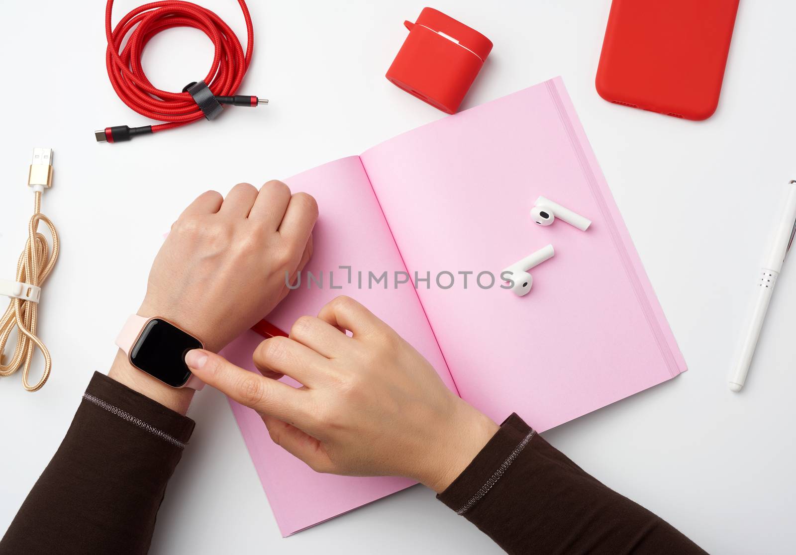 smart watch with a blank black screen is on his left hand, his right hand is touching the watch screen, a freelancer’s workplace with an open notebook, top view, work at home