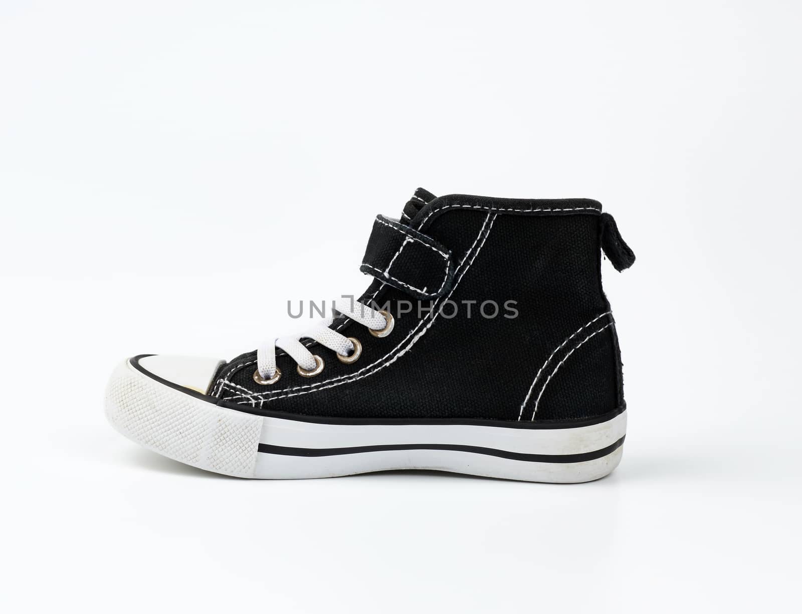 black textile sneaker with white tied shoelaces on a white background, shoes stand sideways