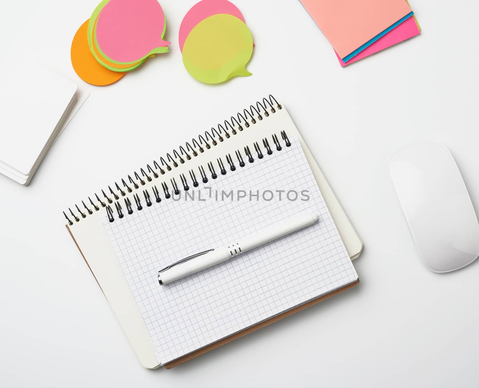 open paper notebooks and pen, computer mouse and green plants in a flowerpot on a white table, freelancer workplace, top view