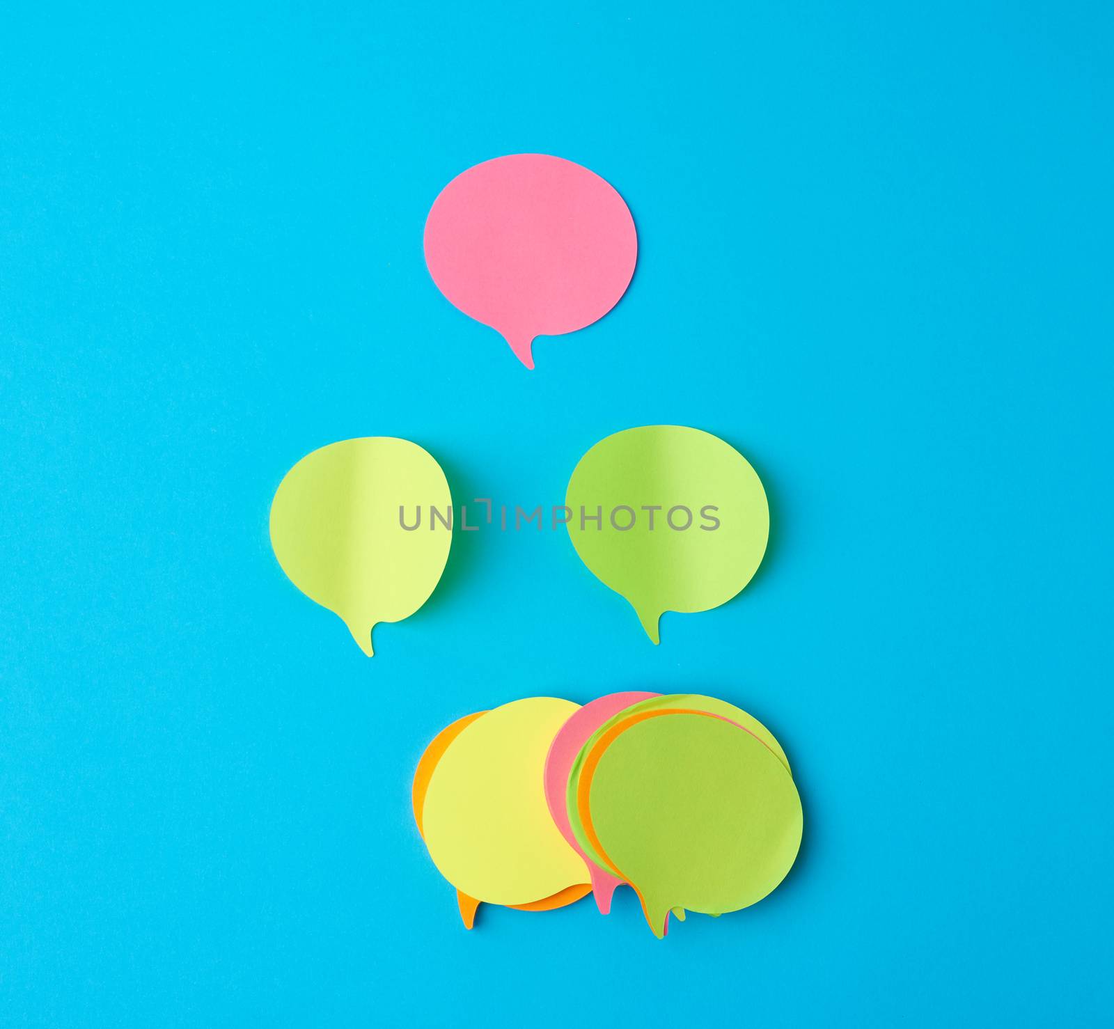 multicolored empty paper stickers in the form of clouds on a blue background, copy space