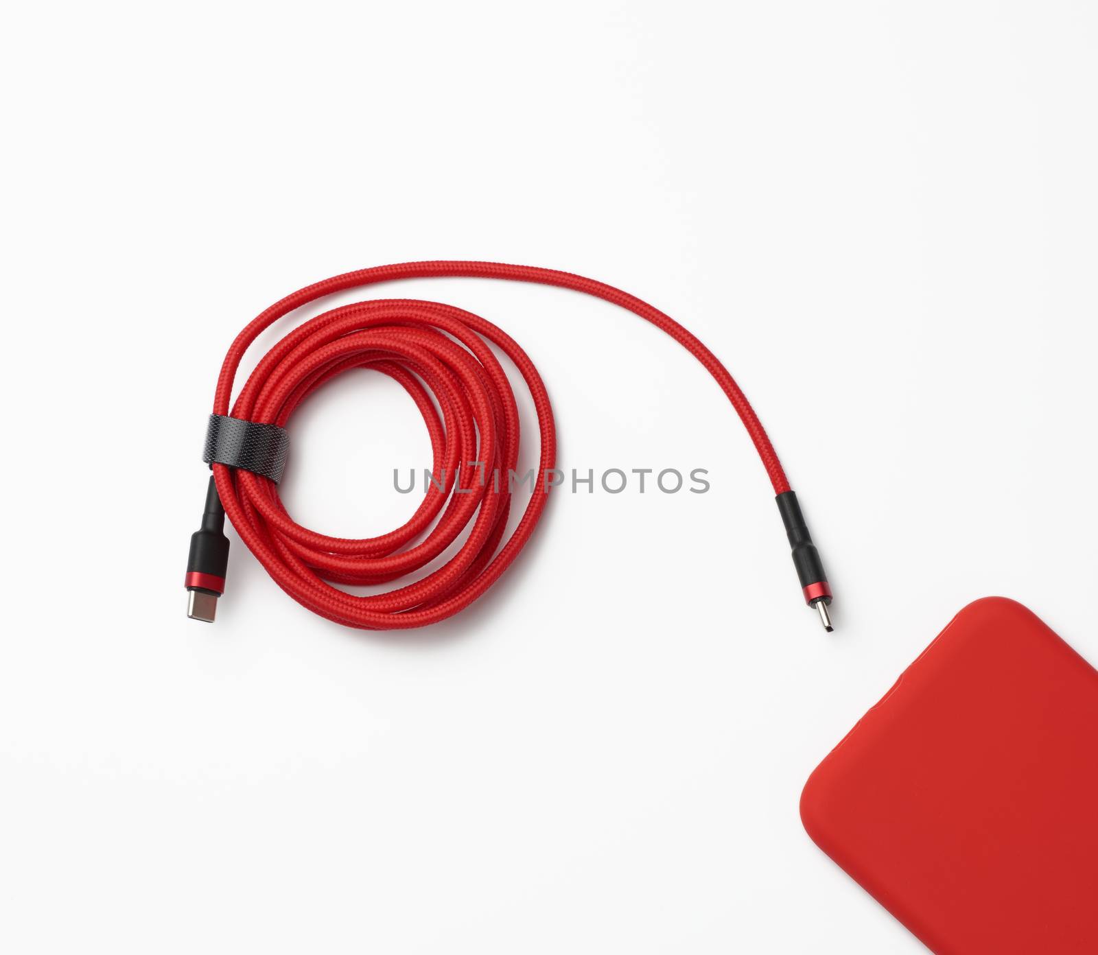 red smartphone and cable in textile braid on a white background, close up, flat lay