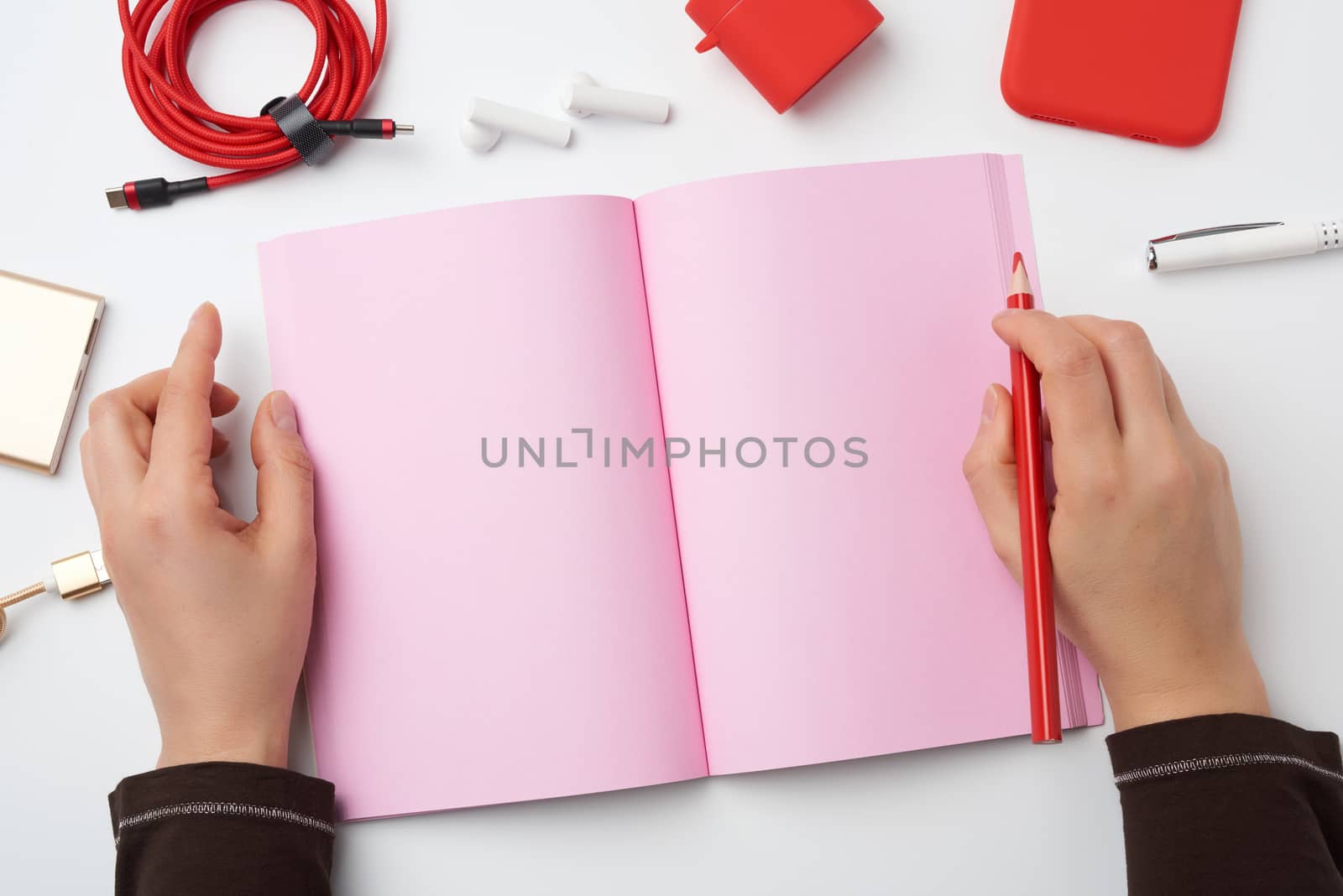 open notebook with blank pink pages and two hands, concept of writing a plan, strategy, freelancer workplace, top view