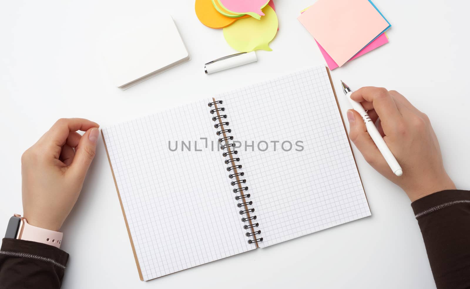 open notebook and two female hands with pen, top view, workplace