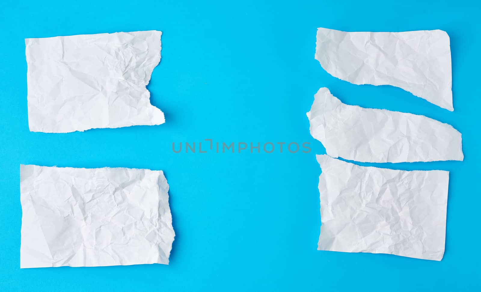 crumpled white sheet of paper torn on a blue background. Paper piece torn edge.
