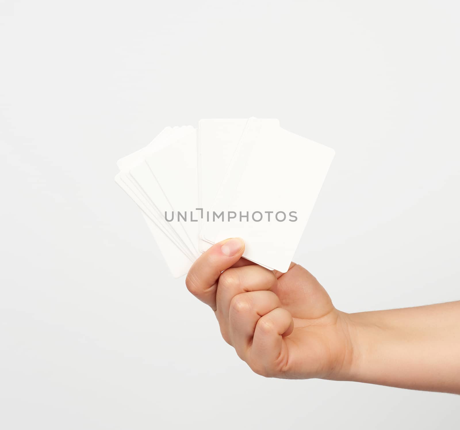 female hand holds a stack of white rectangular paper business cards on a white background, identity concept