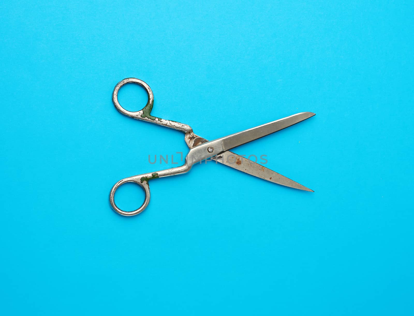 very old vintage metal tailor scissors on a blue background, close up