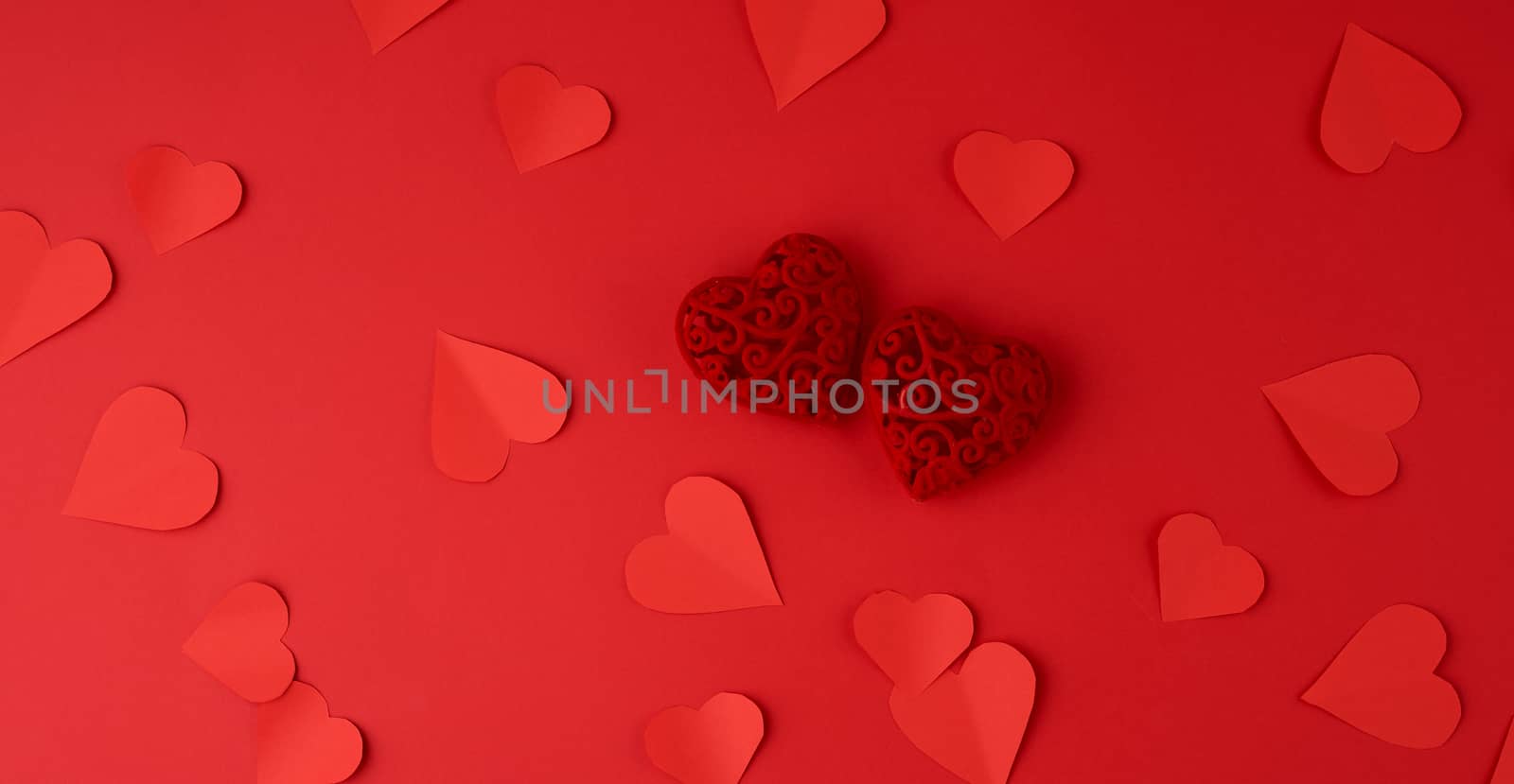 hearts cut out of red paper on a red background, festive backdrop for Valentine's Day, flat lay