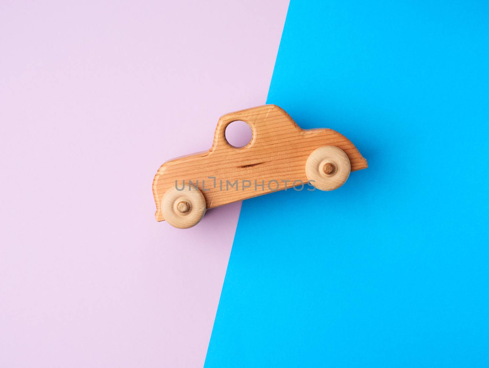 brown children's wooden carved toy car with wheels on a colored background, vintage look