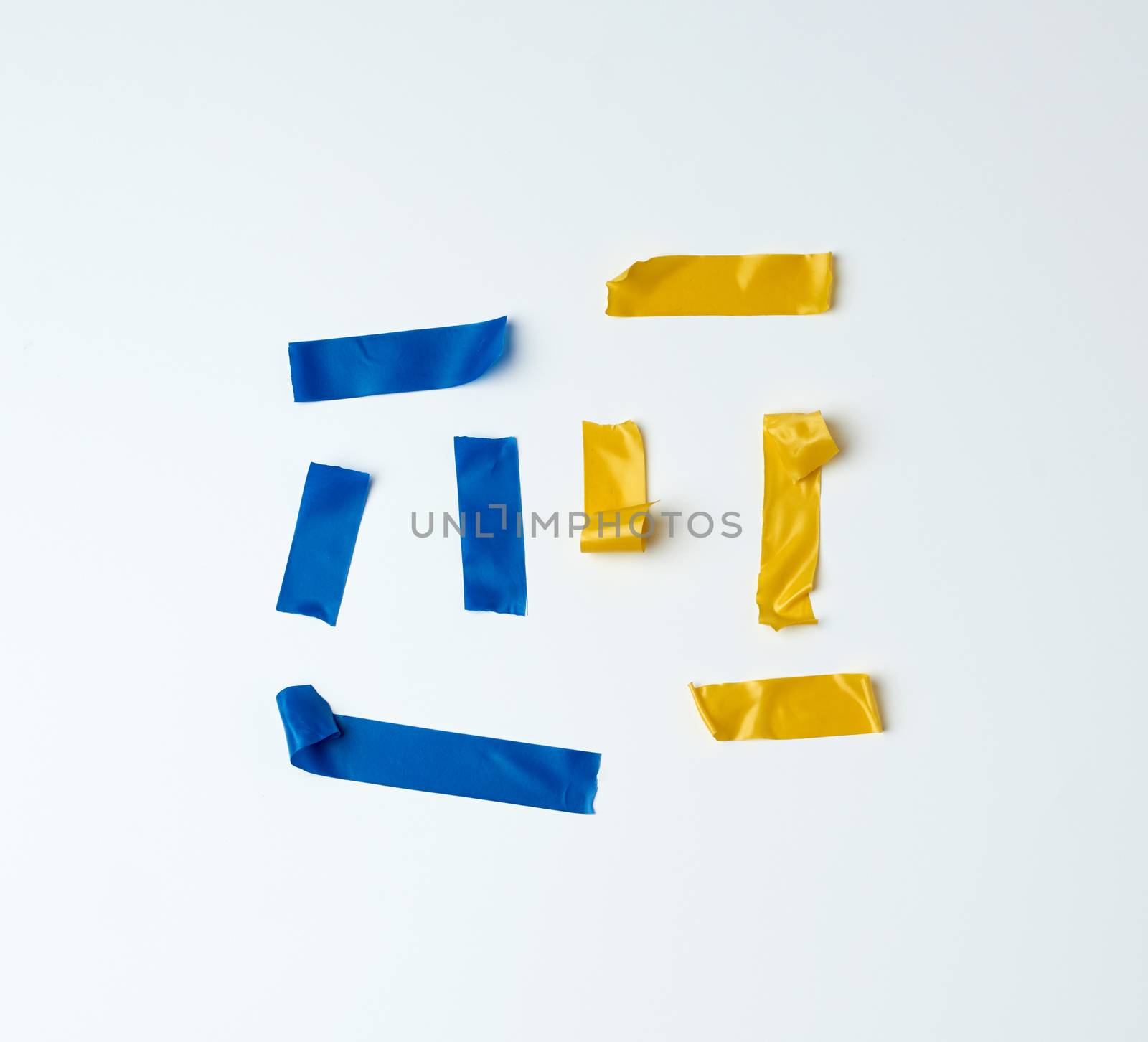 set of torn multicolored rubber pieces of electrical tape glued to a white background, close up