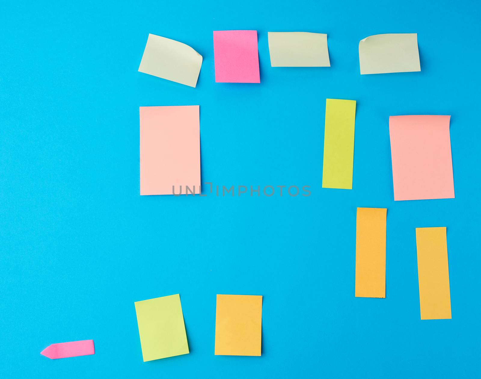 multicolored paper stickers of different shapes on a blue background, backdrop for the designer
