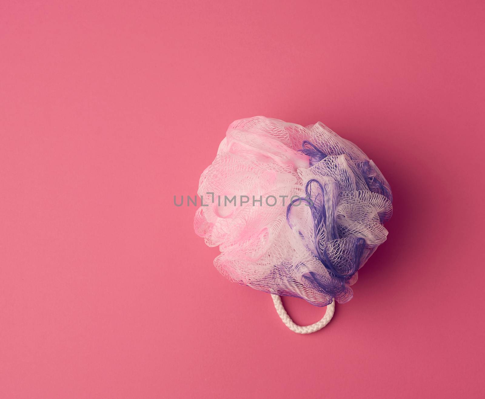 round synthetic washcloth on a pink background, top view