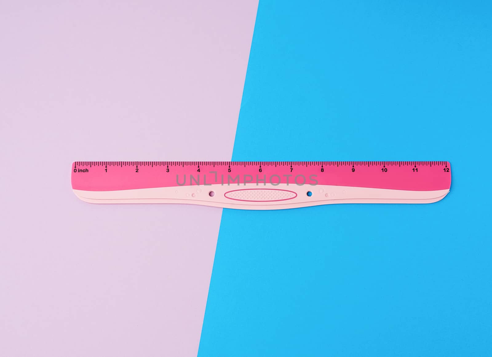 pink plastic ruler on a colored background, top view, flat lay