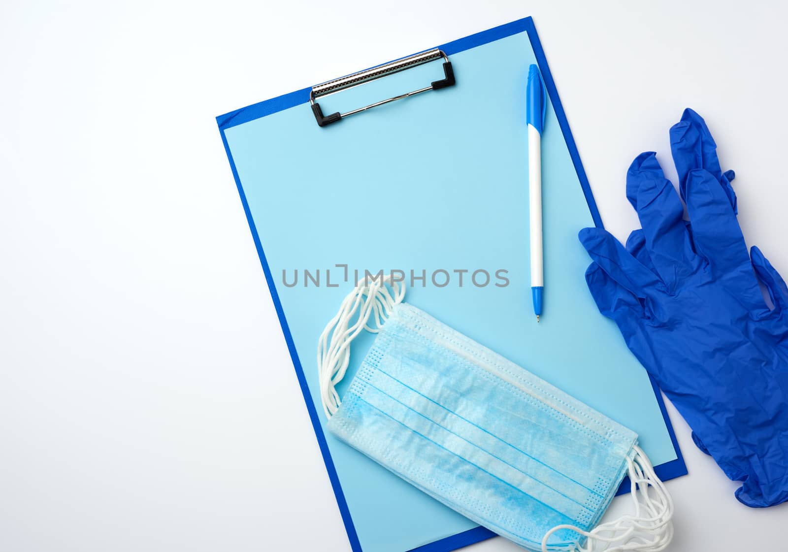  paper holder with a blank blue sheet, disposable blue medical mask on a white background, top view, flat lay