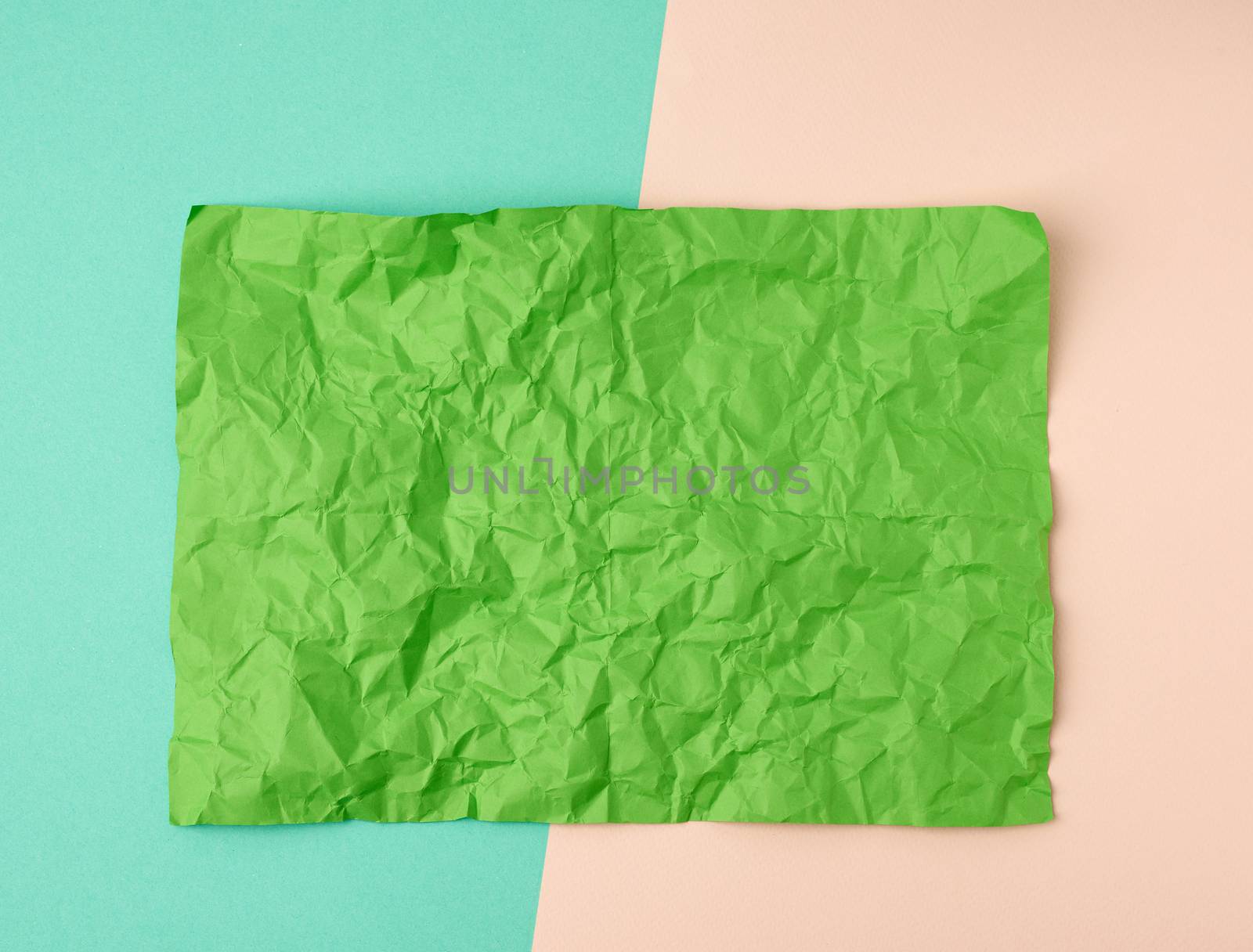 empty crumpled green rectangular sheet of paper a4 on a color background, copy space