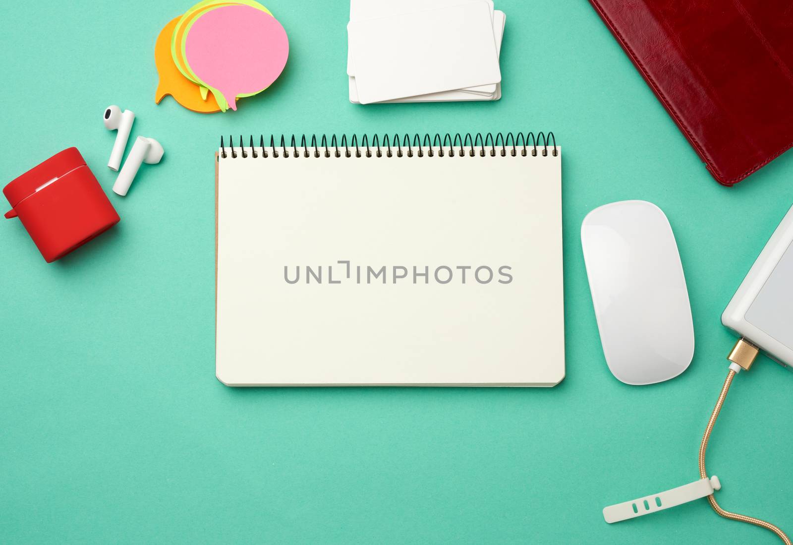open notebook with blank white sheets, computer mouse, wireless headphones and charger, top view