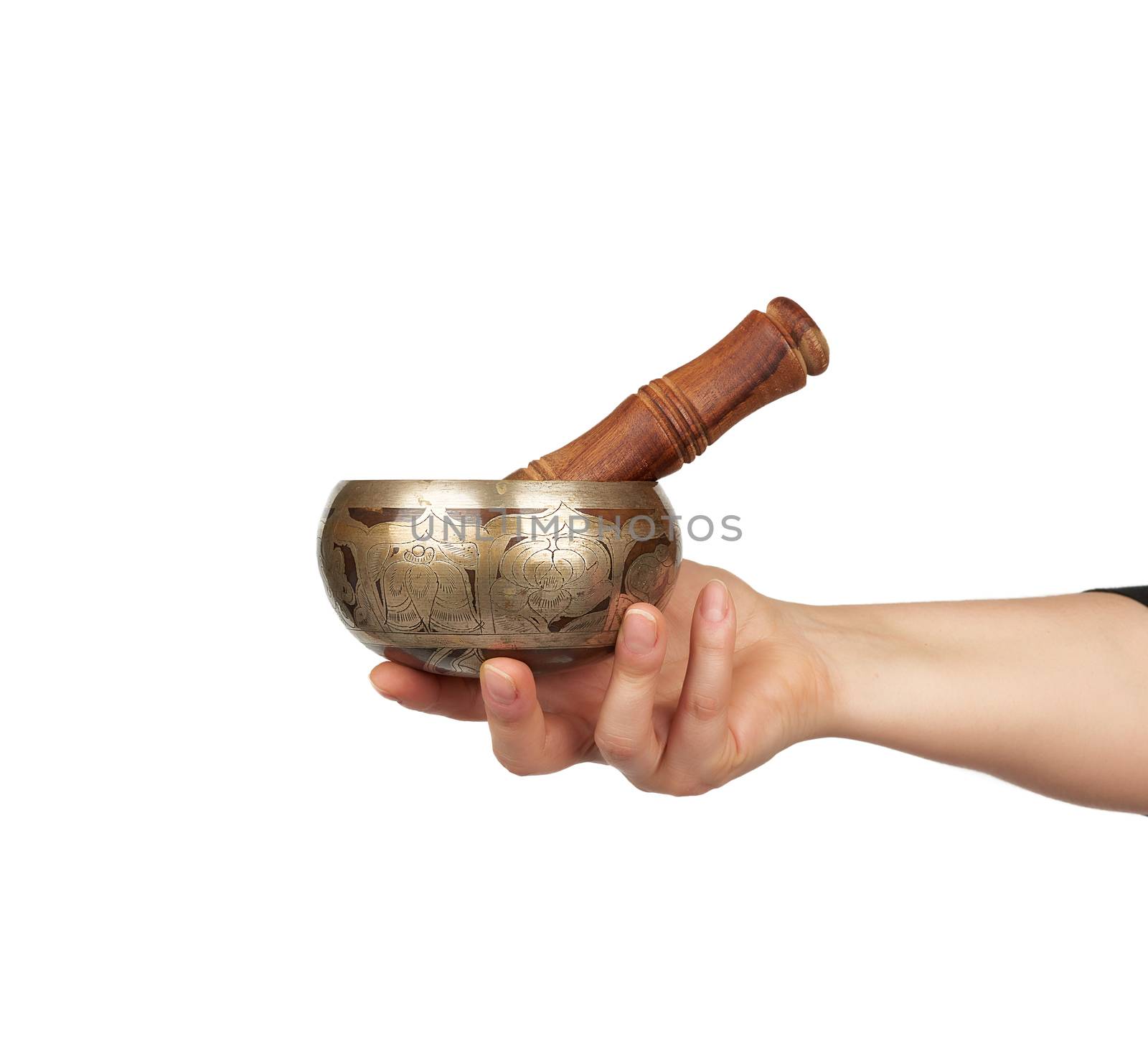 copper singing bowl and wooden stick in female hand on white background, close up