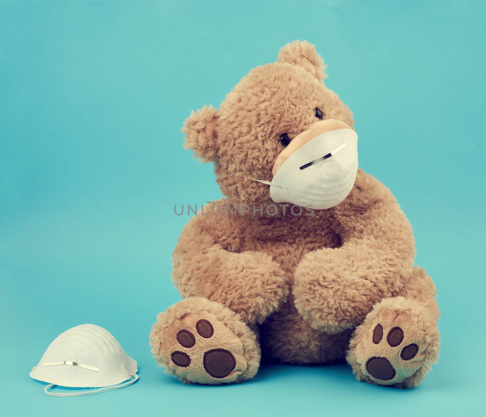 big teddy bear are sitting in medical masks on a blue background, concept of protection from respiratory disease, virus and individual respiratory protection