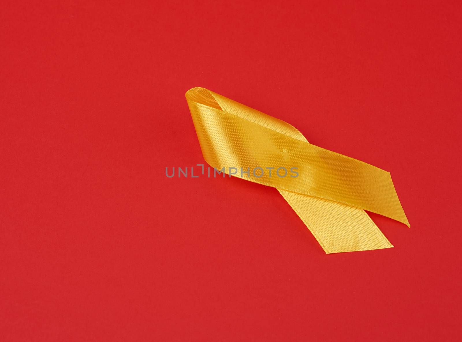 yellow silk ribbon loop on a red background. Sarcoma bone cancer awareness, copy space