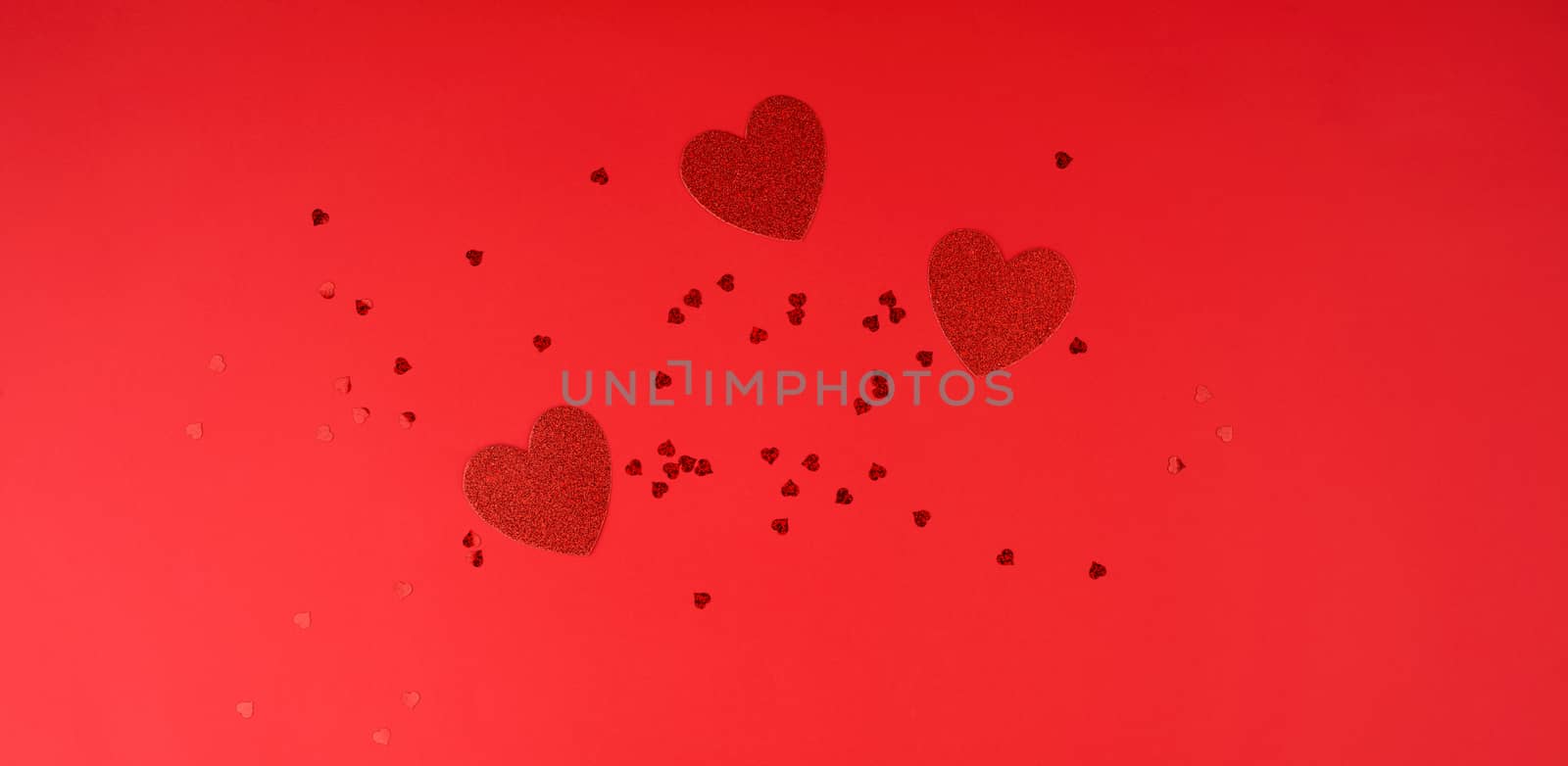 paper red shiny decorative hearts on a red background, abstract festive backdrop for valentines day february 14