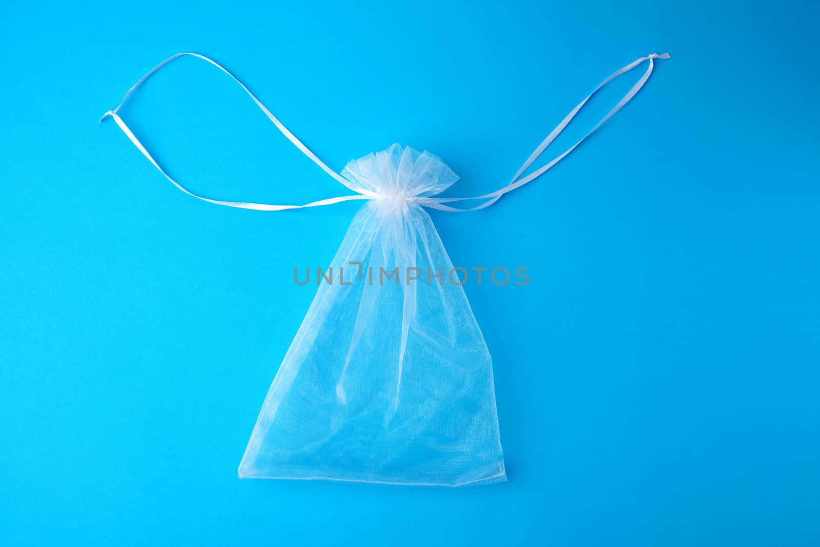 bag made of white transparent synthetic fabric for gifts and cosmetics on a blue background, top view