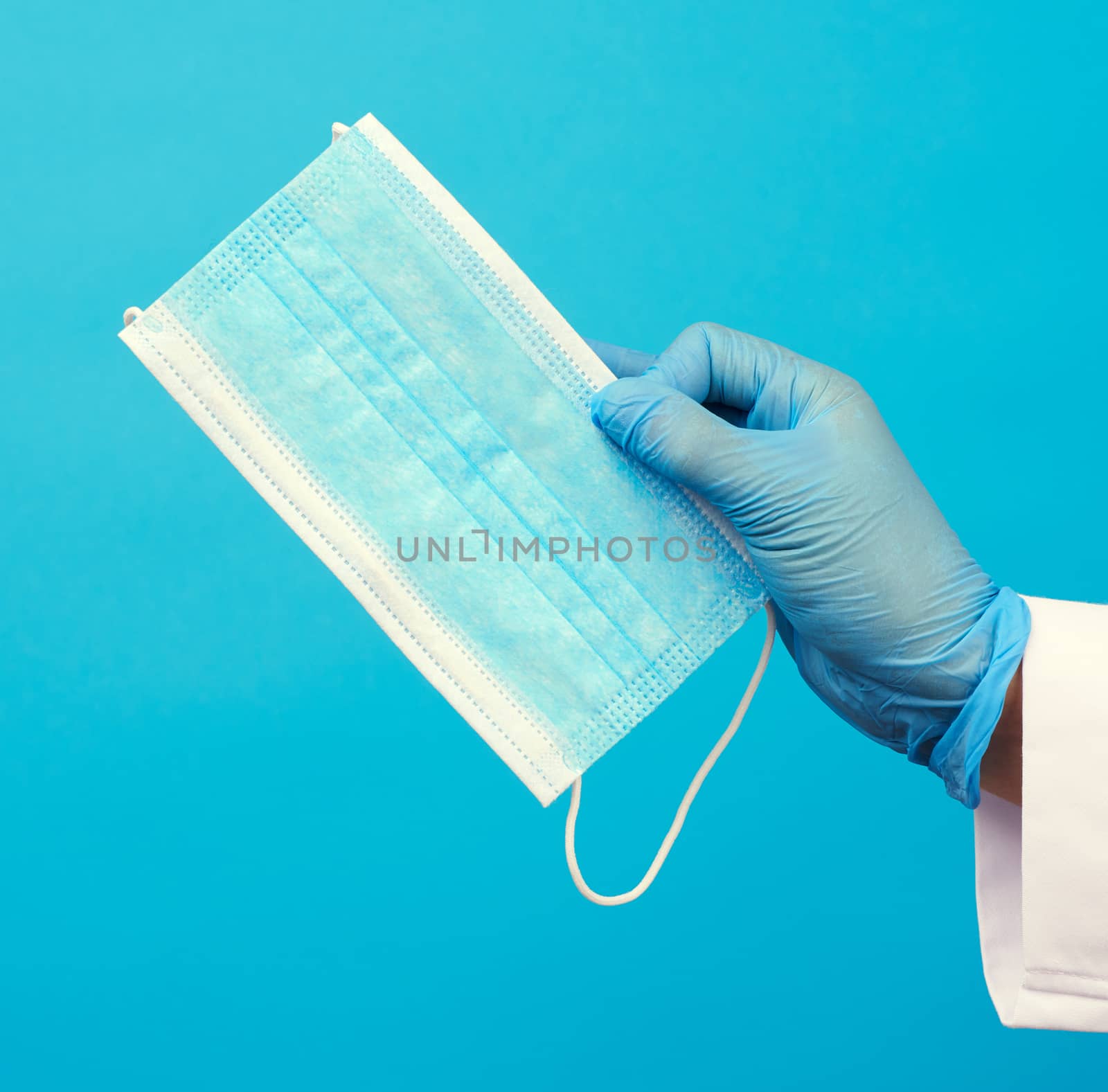 blue disposable mask made of non-woven material on a blue background, protective accessory for the respiratory tract from the virus