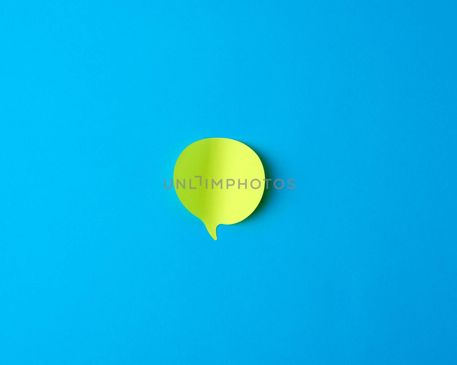 green empty paper sticker in the form of cloud on a blue background, copy space