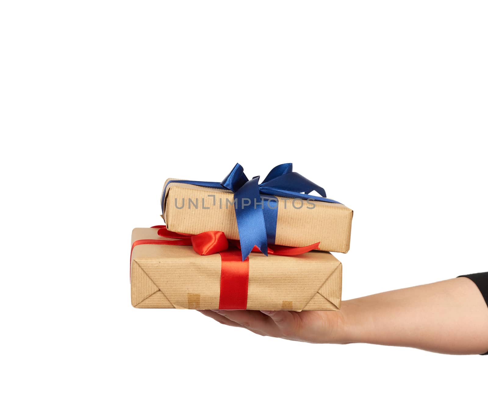 hand holds a stack of wrapped gifts in brown craft paper with tied silk bows, subject is isolated on a white background