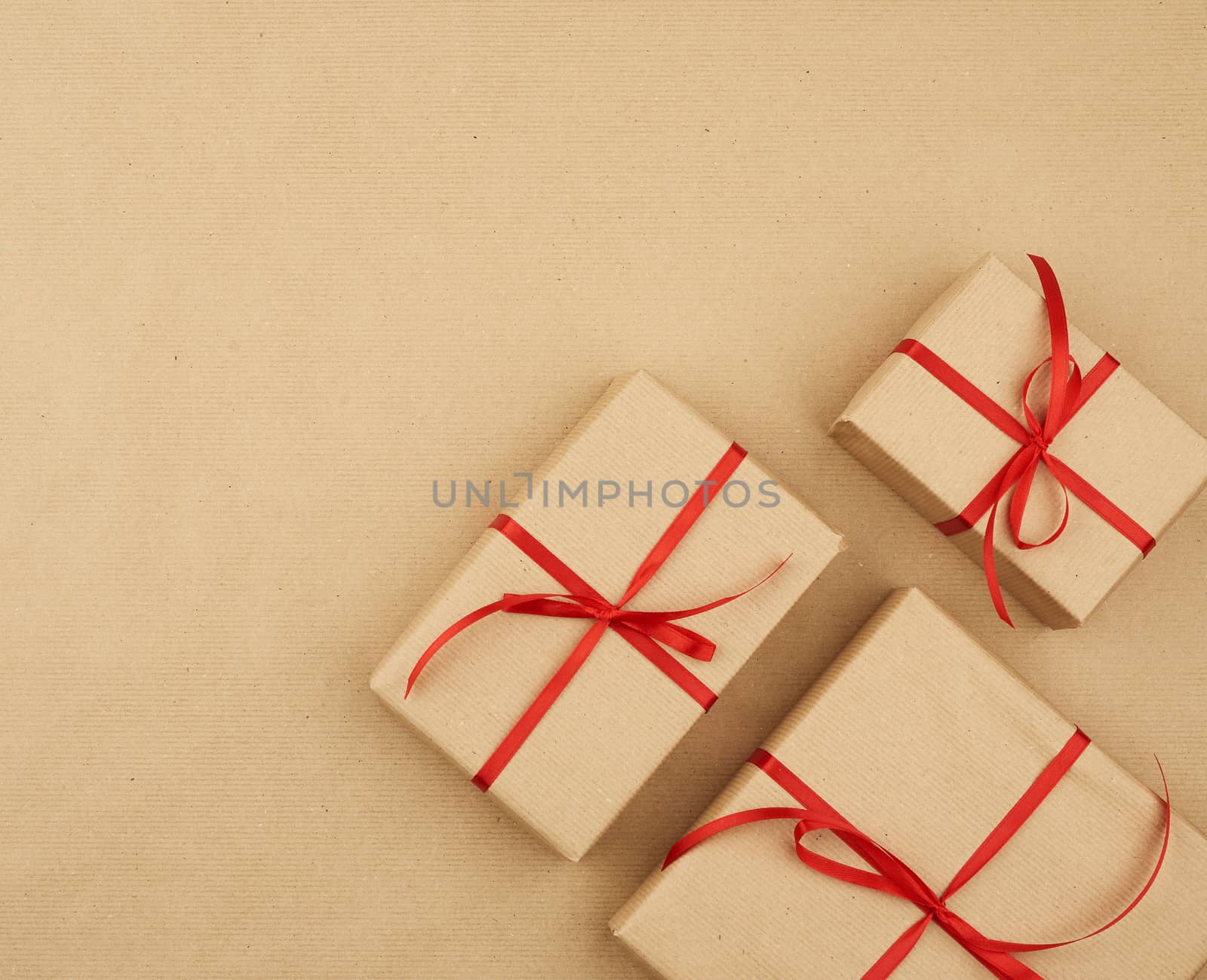 gift wrapped in brown kraft paper and tied with a thin silk ribbon on a background of paper, top view. Congratulations on Valentine's Day February 14