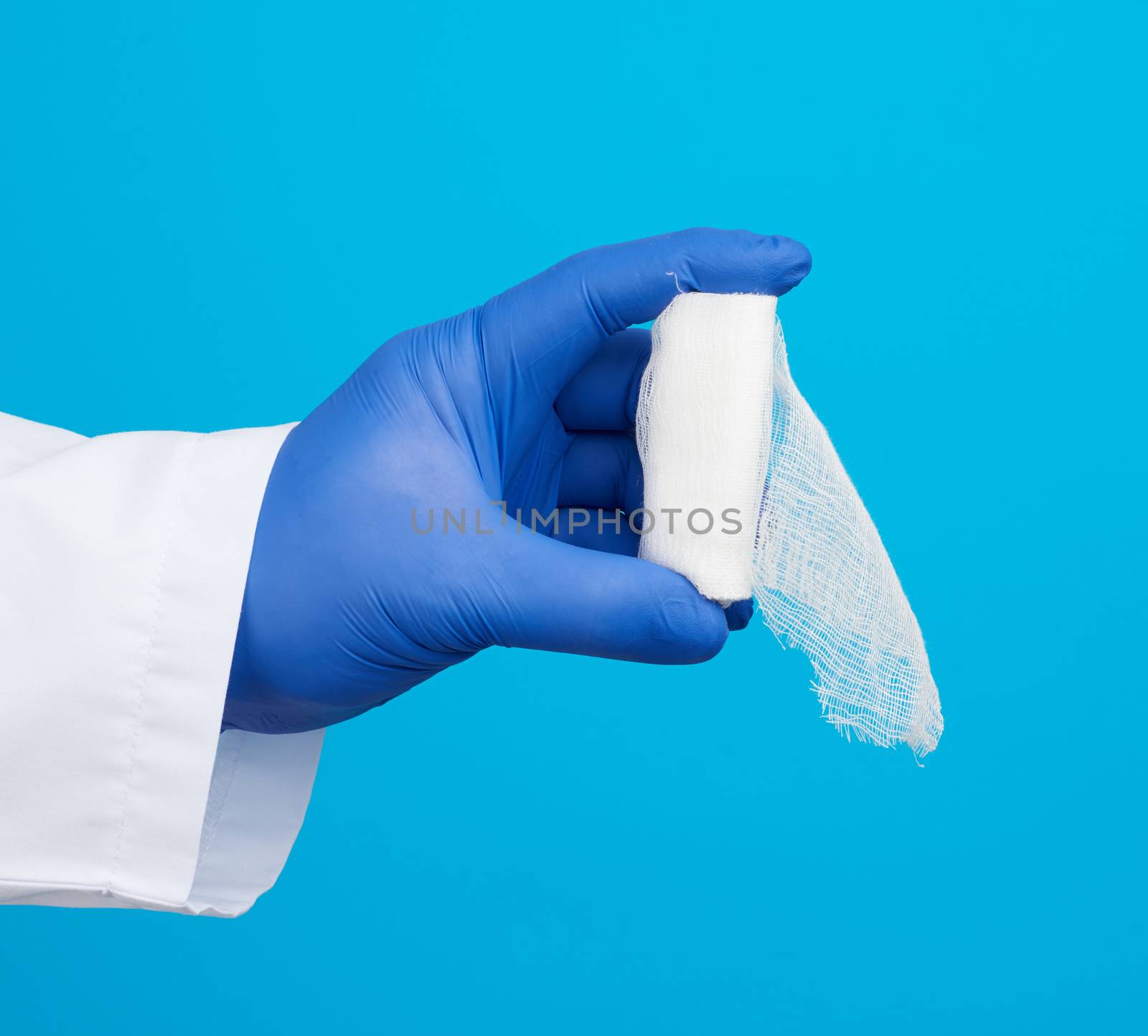 male hand in blue sterile gloves holds a white twisted gauze medical bandage on a blue background, treatment of injuries