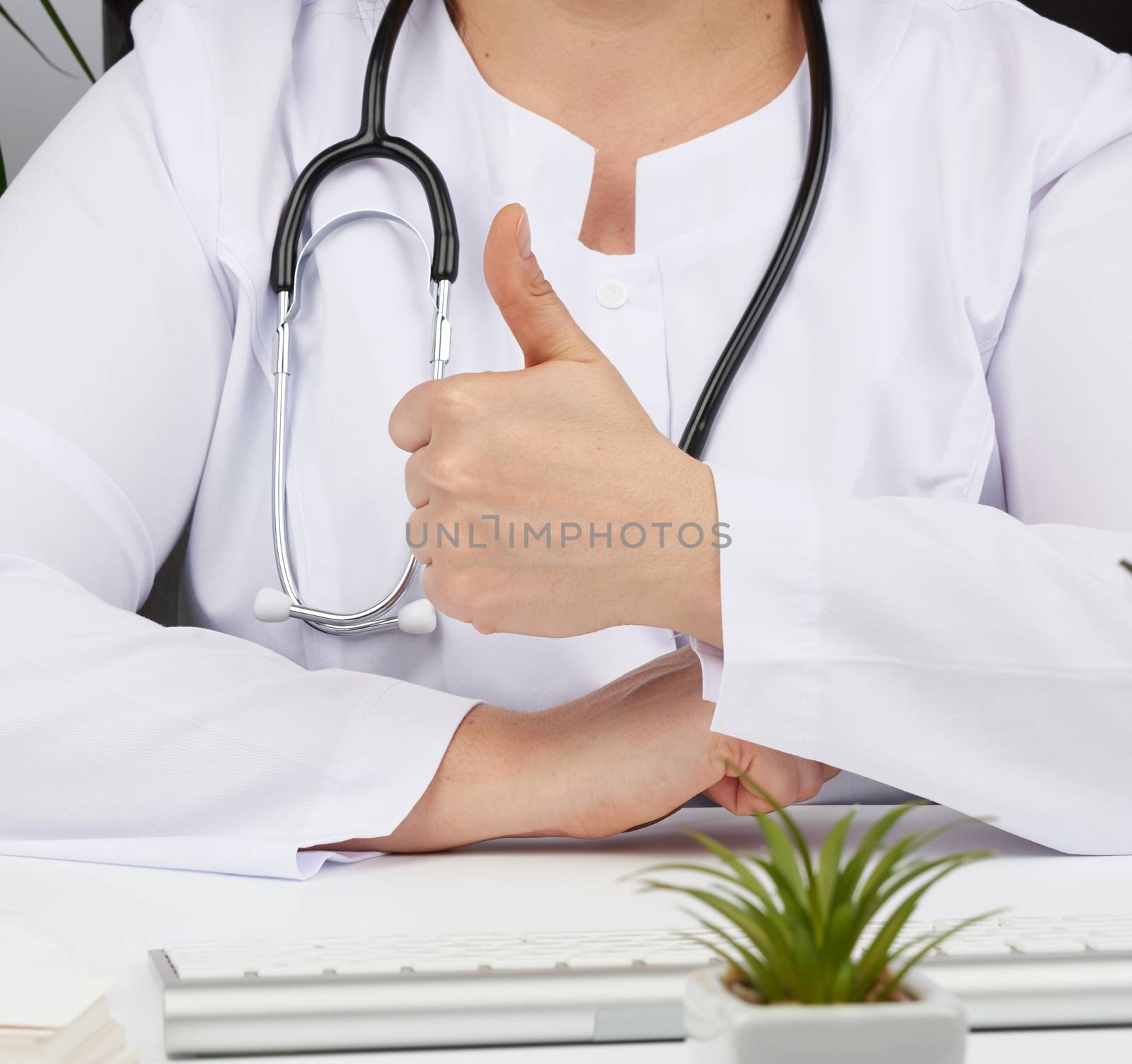 medic woman in white coat showing like gesture in hand, approval concept, close up