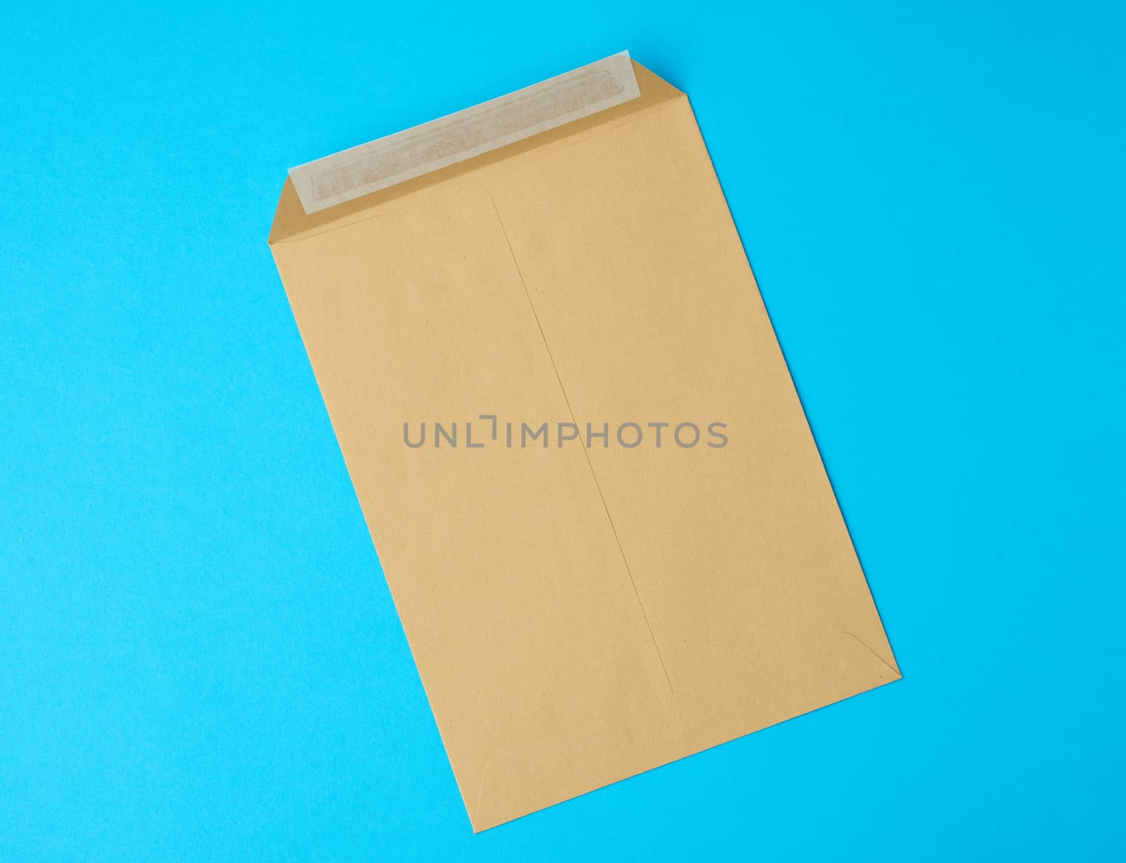 brown blank paper envelope on a blue background, flat lay