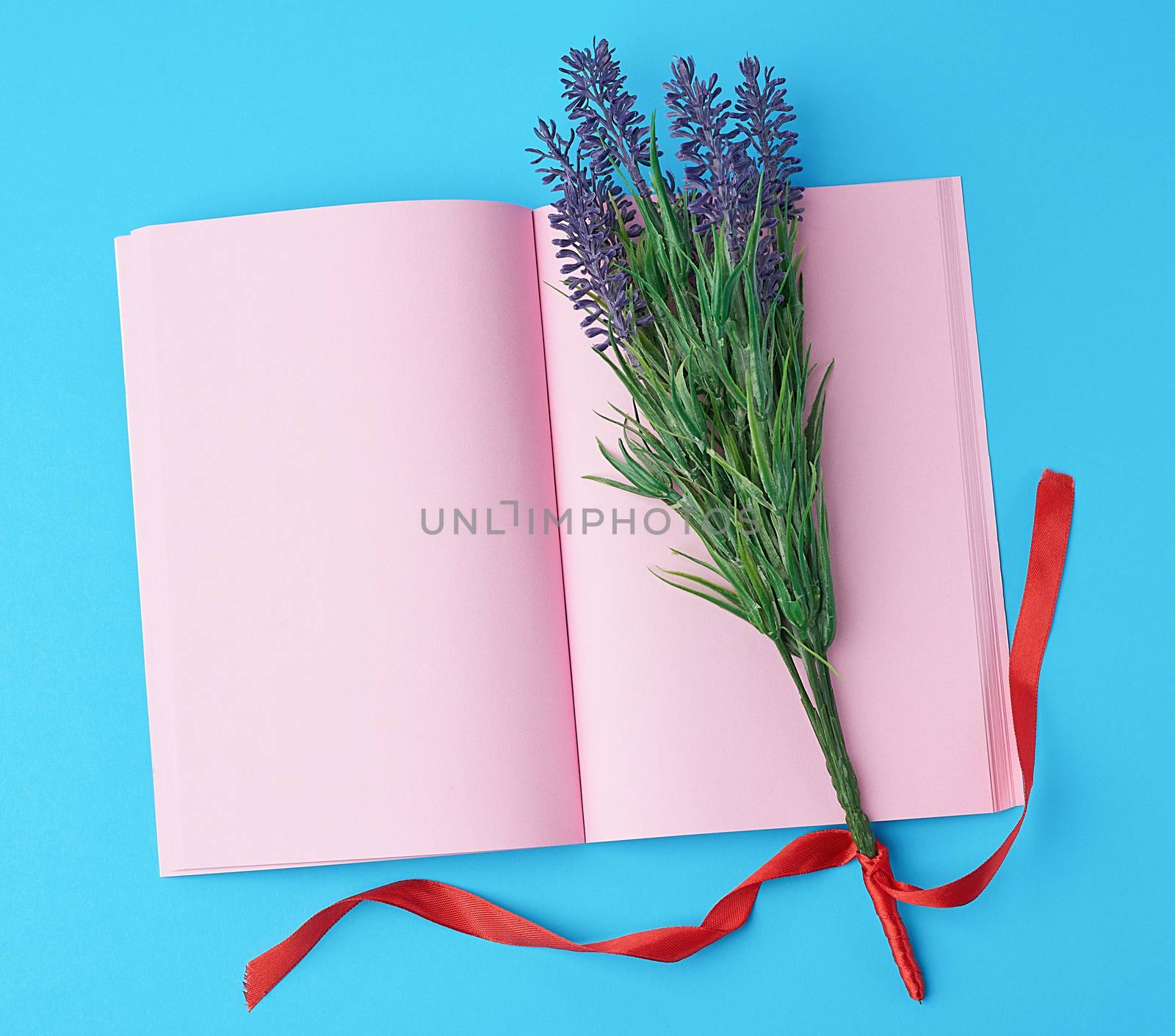 open notebook with blank pink pages, bouquet of lavenders on a blue background, top view, flat lay