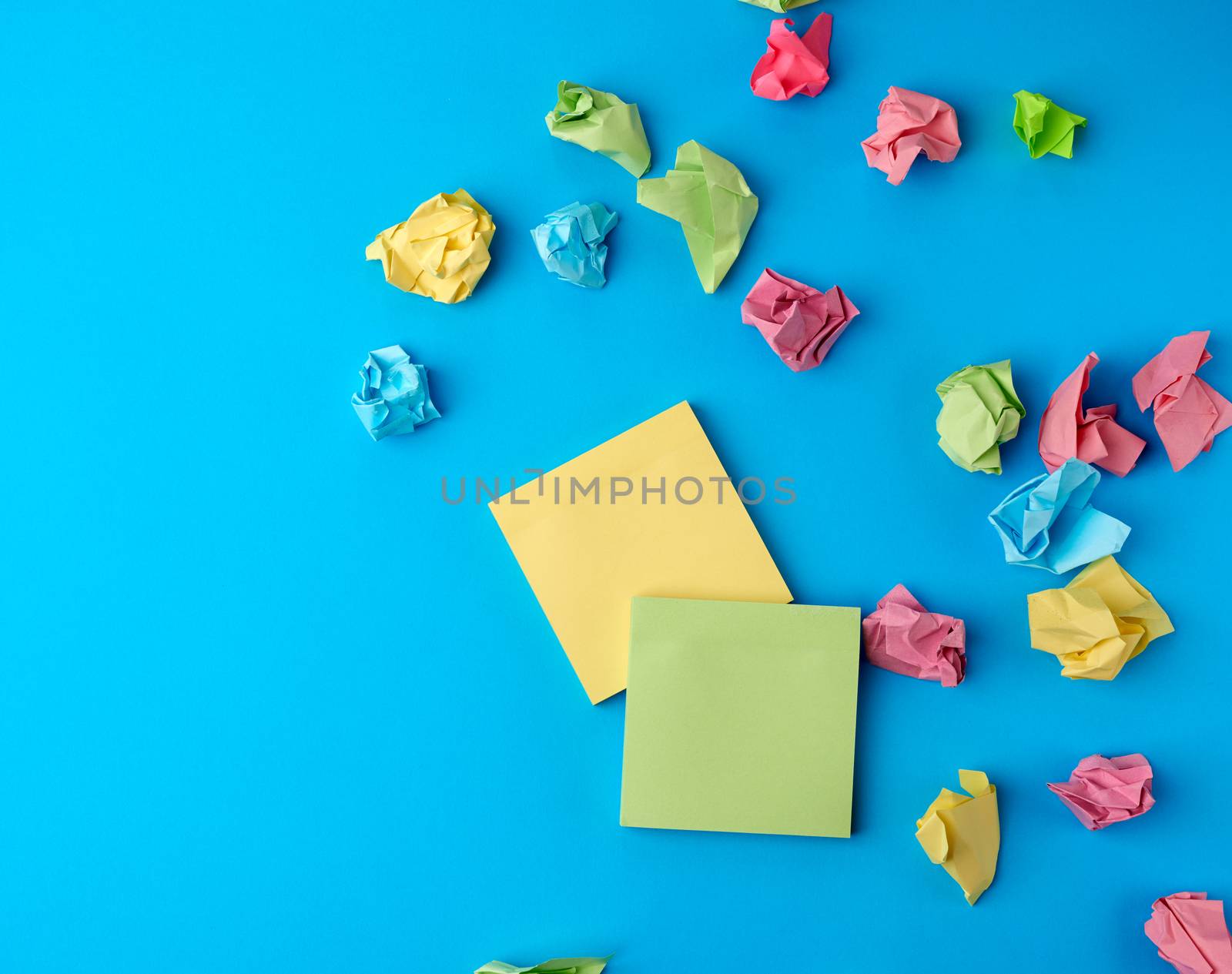 multicolored blank paper stickers of different colors on a blue background, copy space