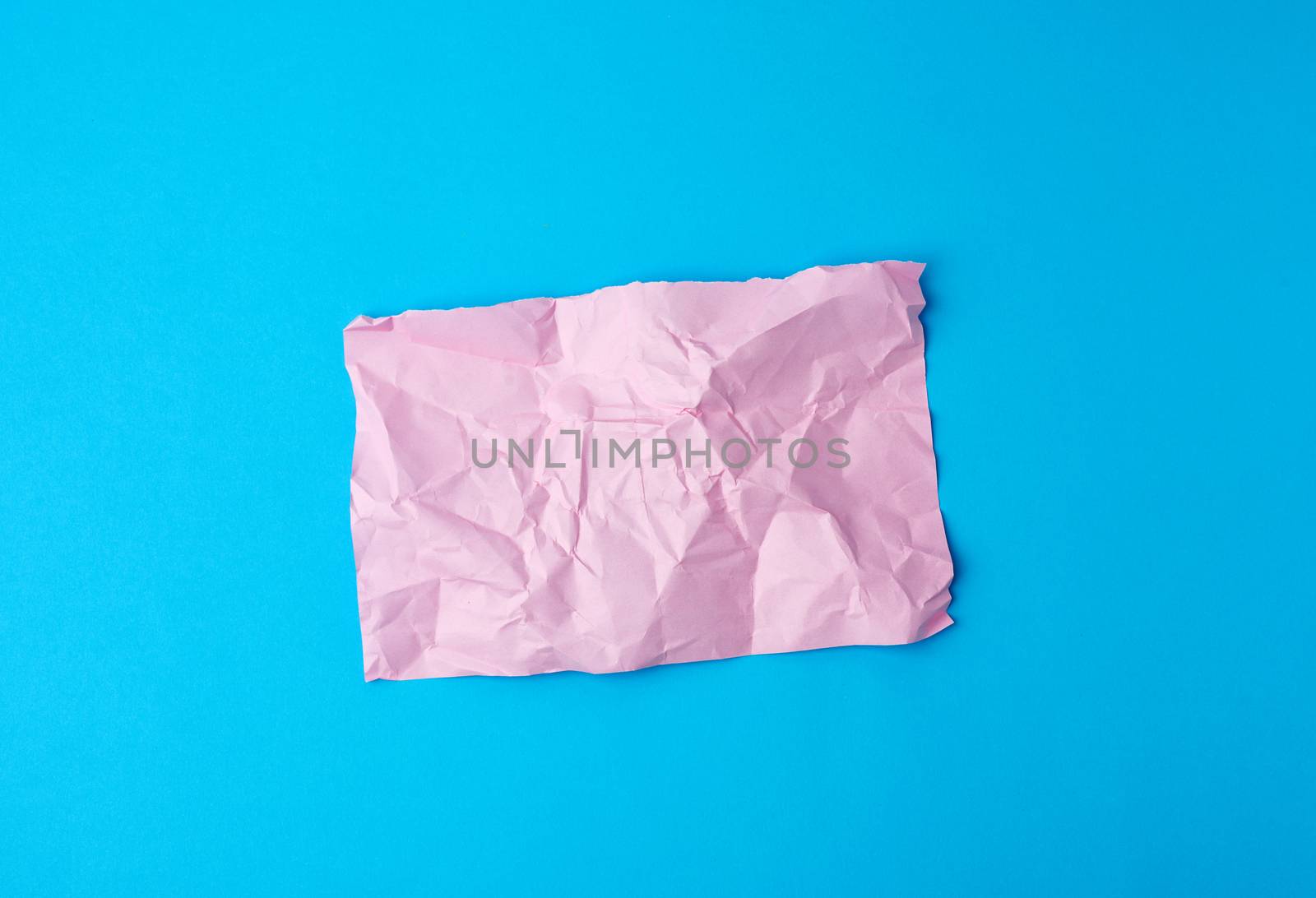 empty crumpled pink rectangular sheet of paper a4 on a blue background, copy space