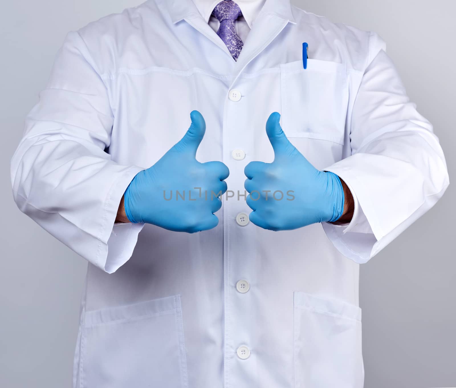 doctor in a white coat and tie shows with his hand a gesture like, wearing blue latex medical gloves, white background