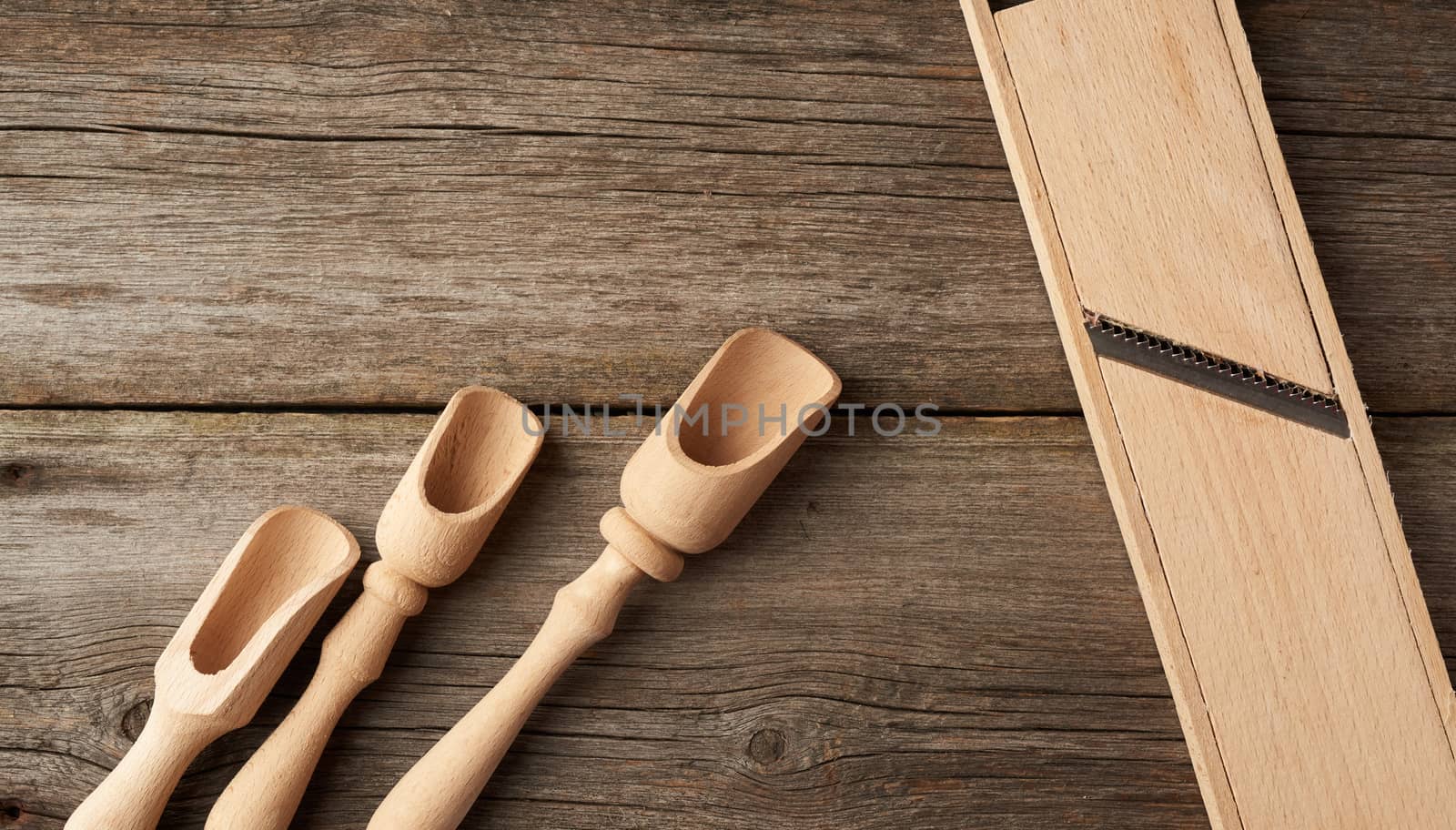 empty wooden spoon and vintage grater for vegetables on a gray wooden background, top view
